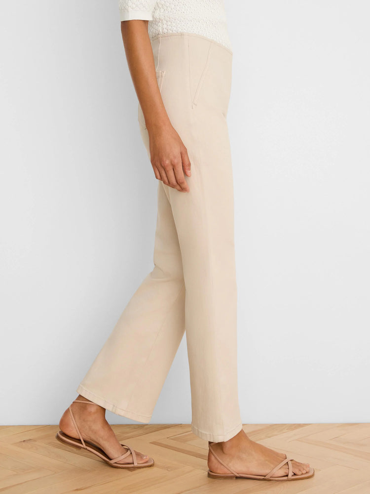 Light beige boot-cut jeans, side view on a model, fitted through thigh, subtle flare at hem.