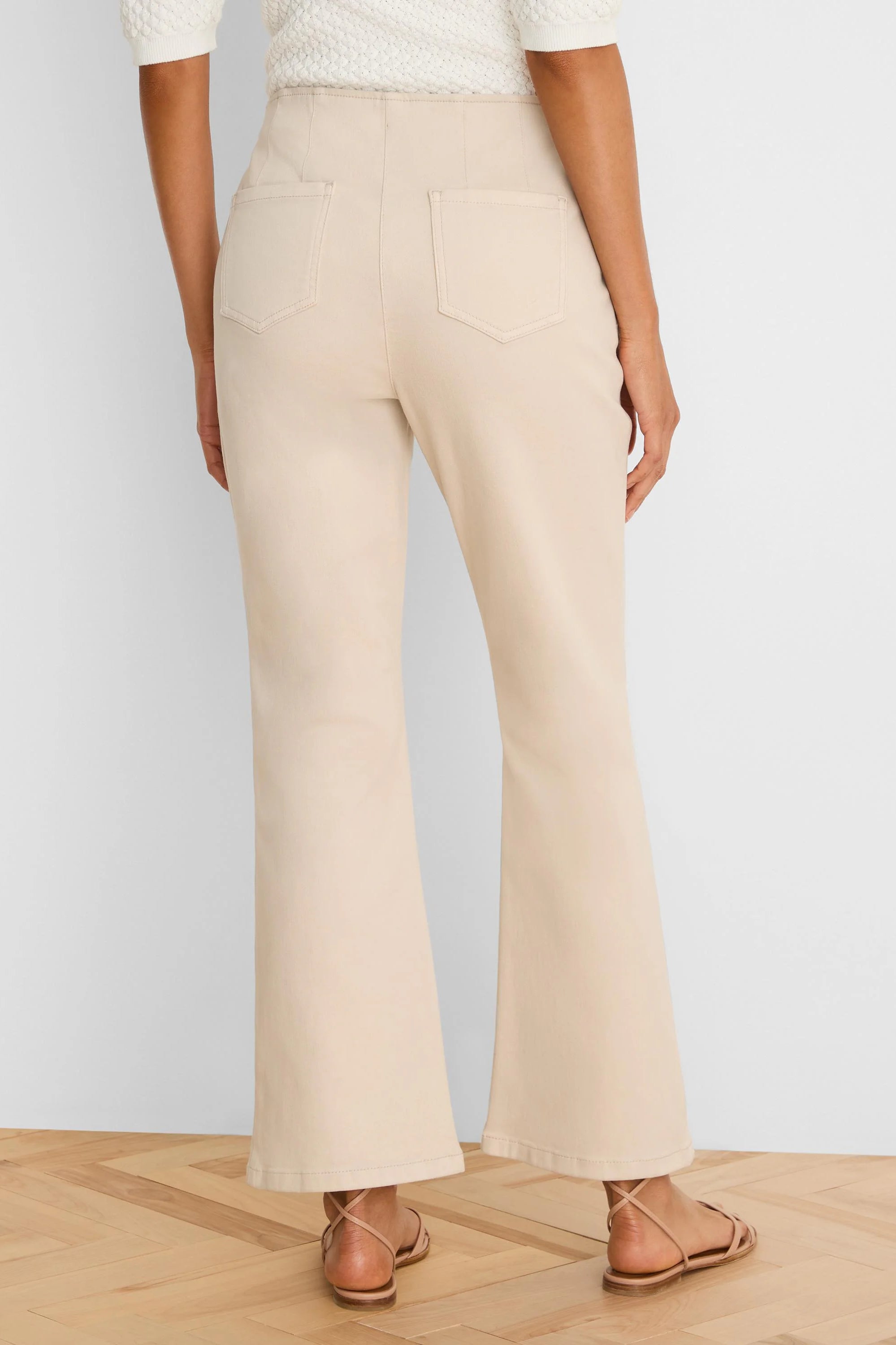 Light beige high-waisted bootcut jeans, viewed from behind, with back patch pockets and visible stitching.