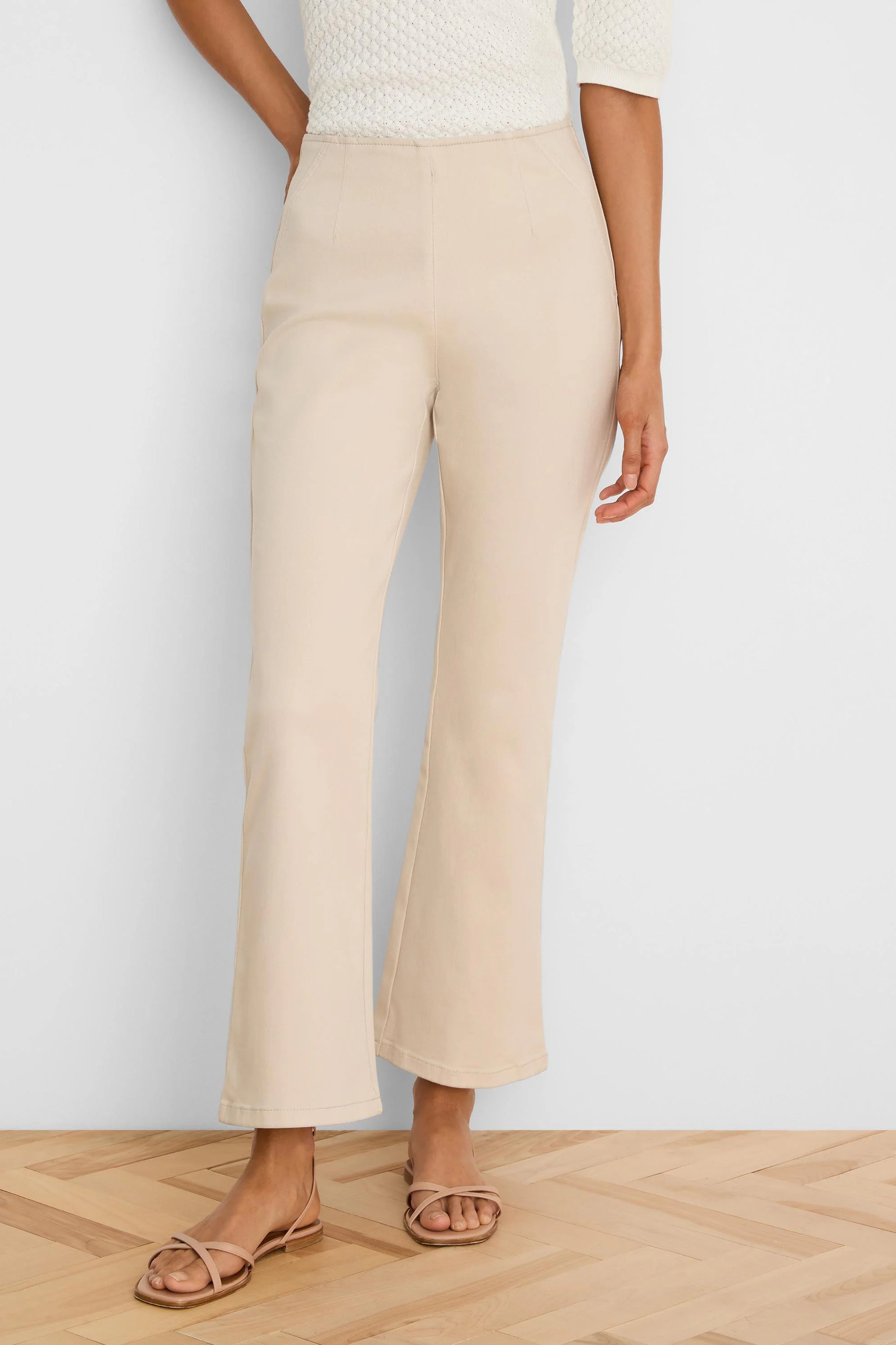 Pale beige boot-cut jeans, high-waisted, fitted through the thigh, with a subtle ankle flare.