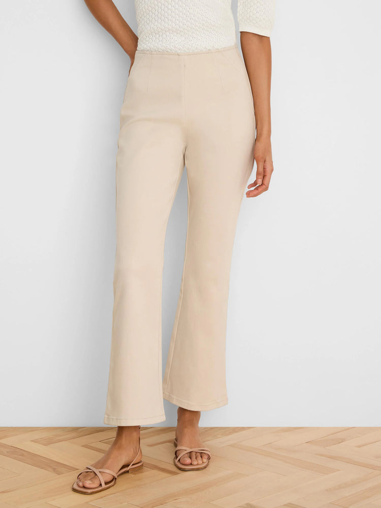 Pale beige boot-cut jeans, high-waisted, fitted through the thigh, with a subtle ankle flare.