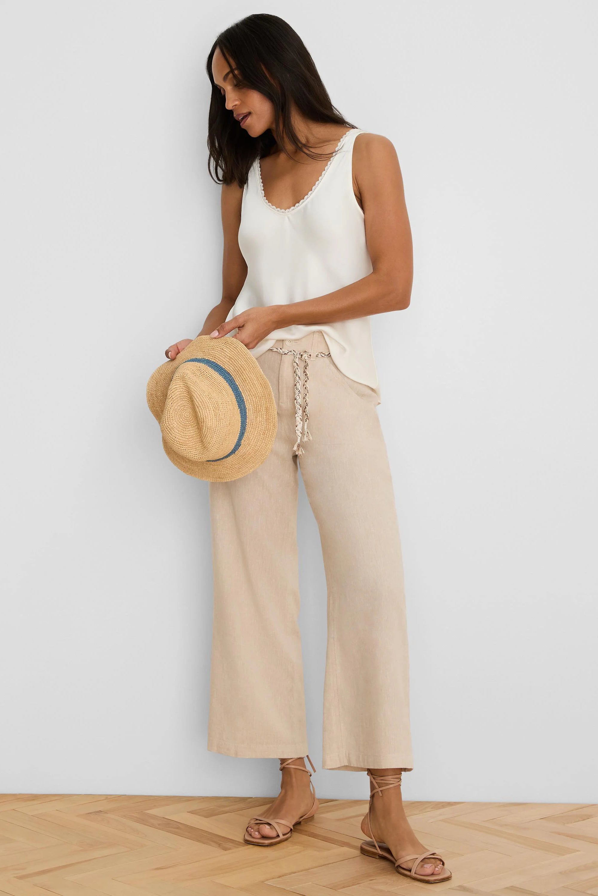 Light beige wide-leg linen crop pants feature a textured braided belt.