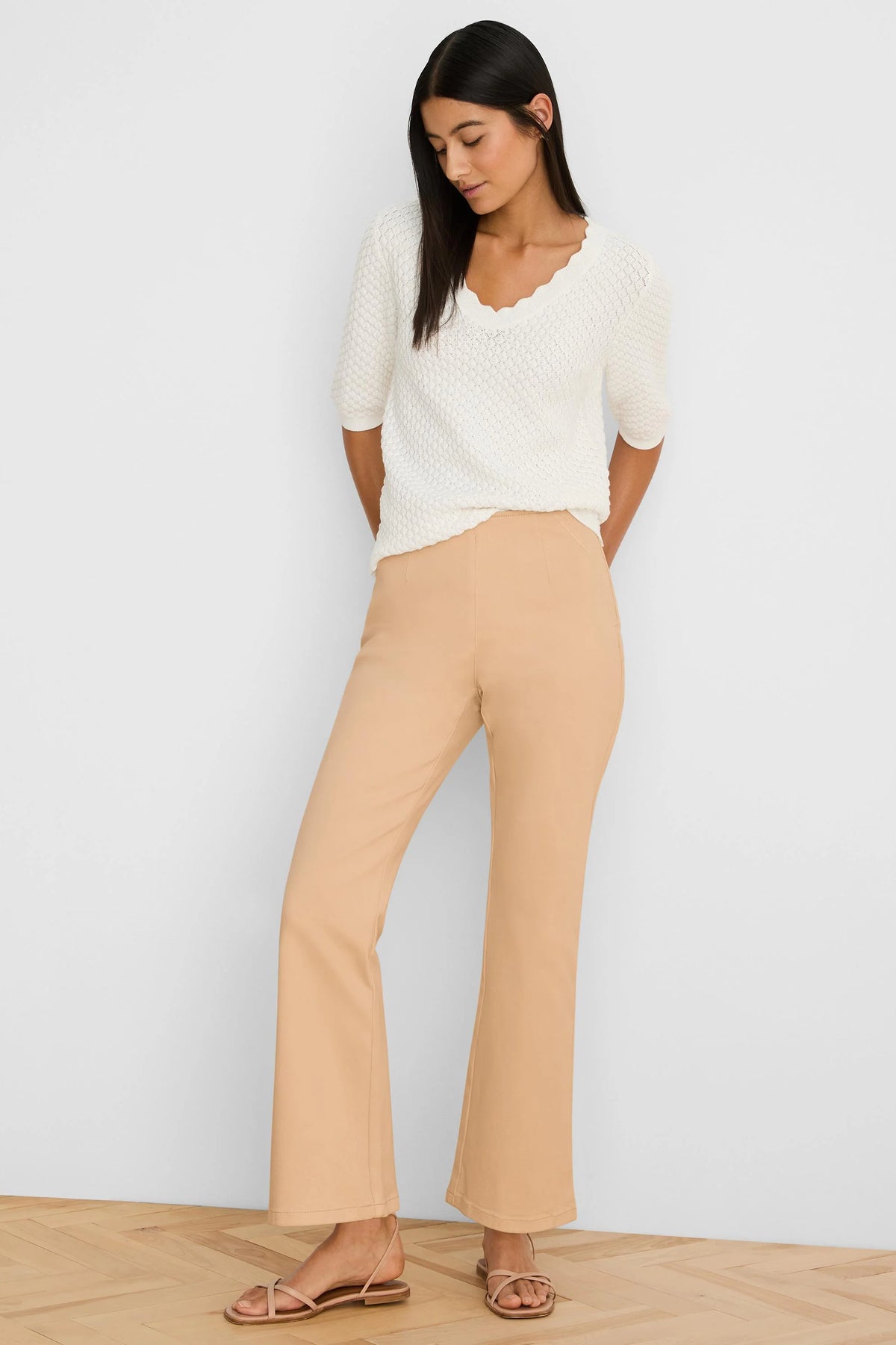Smooth tan bootcut jeans with a flat front and subtle vertical seams down the legs.