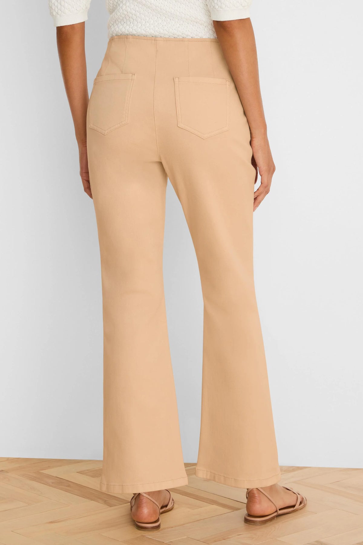 Light tan high-waisted bootcut jeans, seen from the back. Features two patch pockets and a flared leg opening.