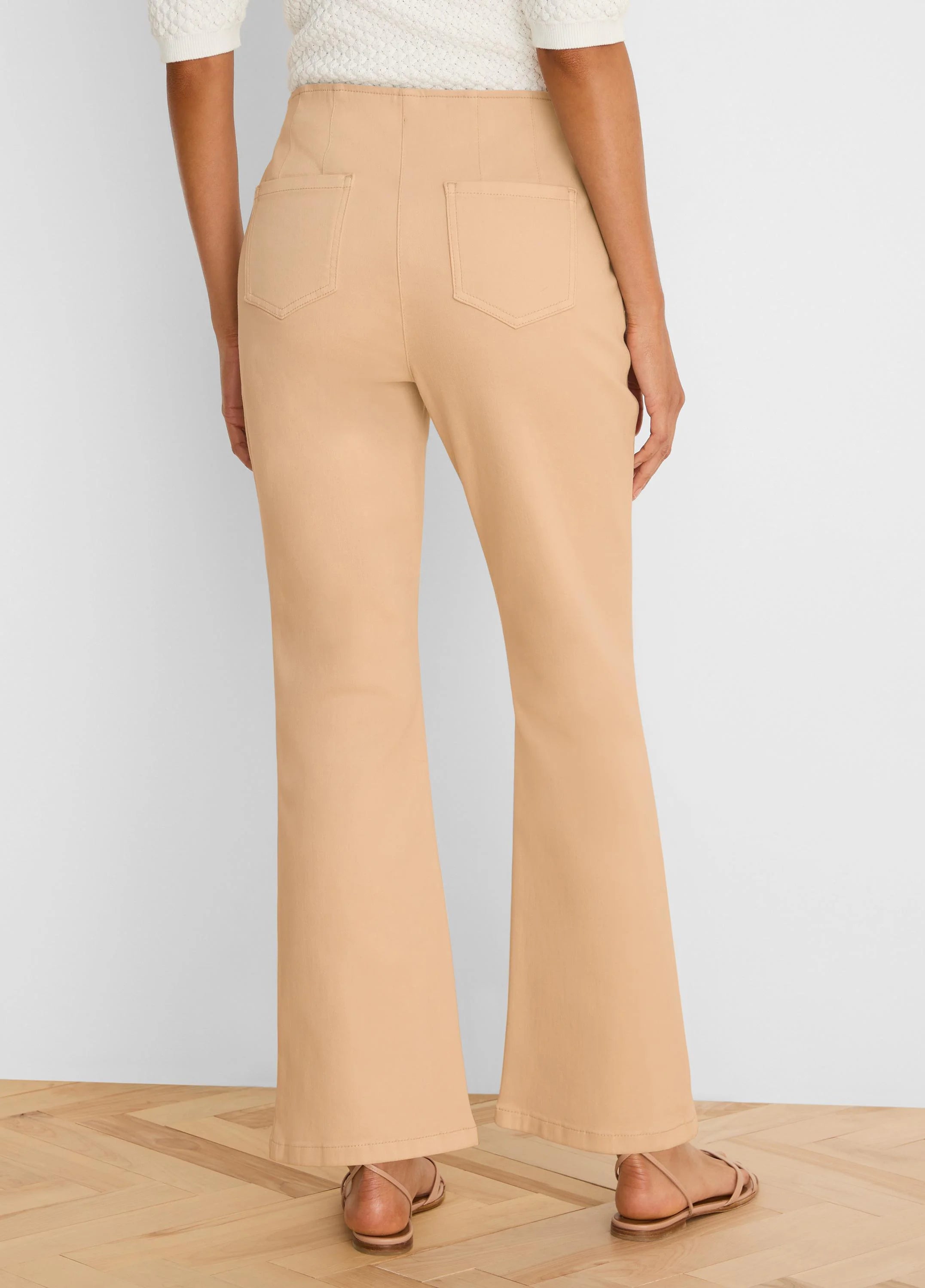 Light tan high-waisted bootcut jeans, seen from the back. Features two patch pockets and a flared leg opening.