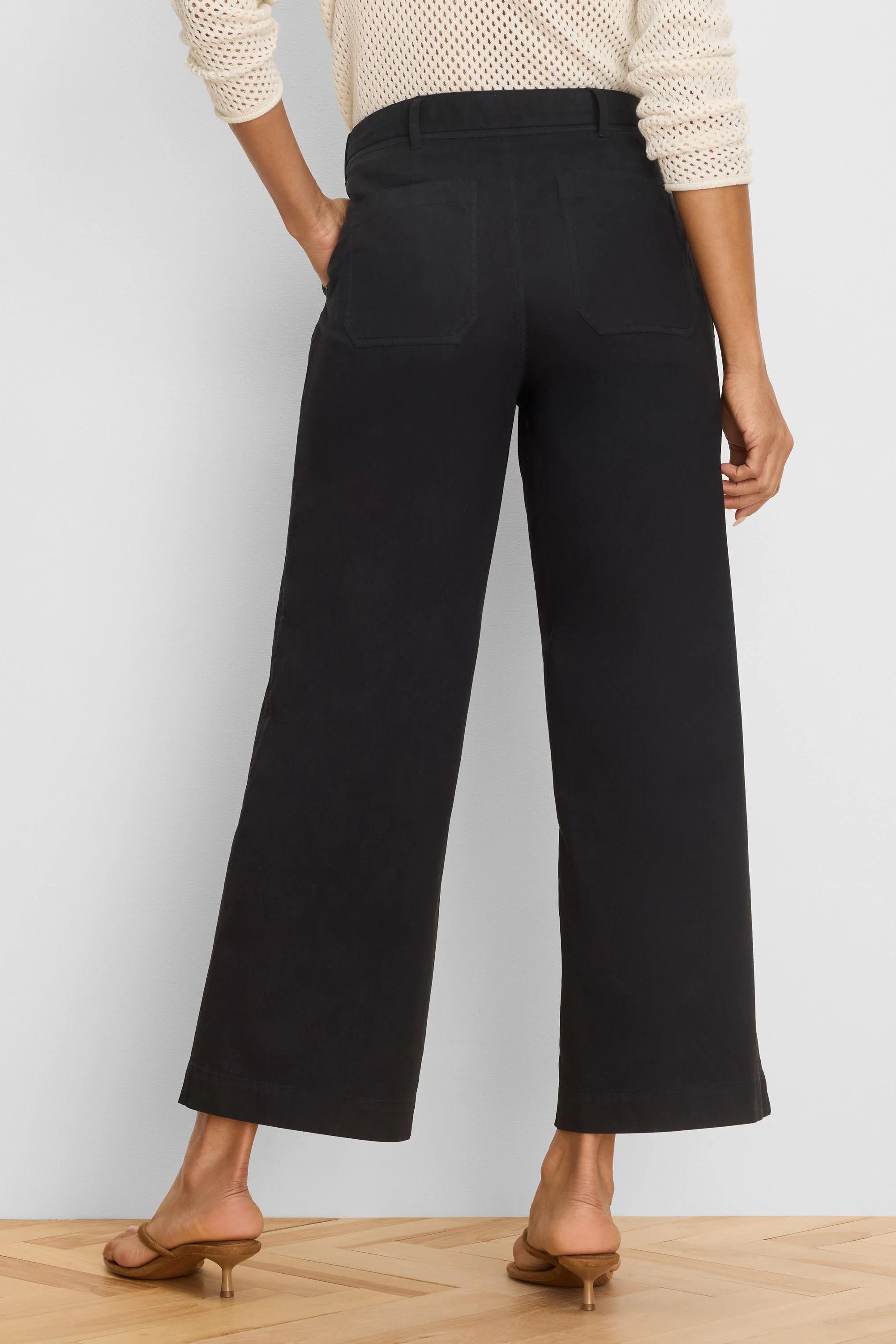 Rear view of black wide-leg ankle pants with visible belt loops and two back patch pockets.