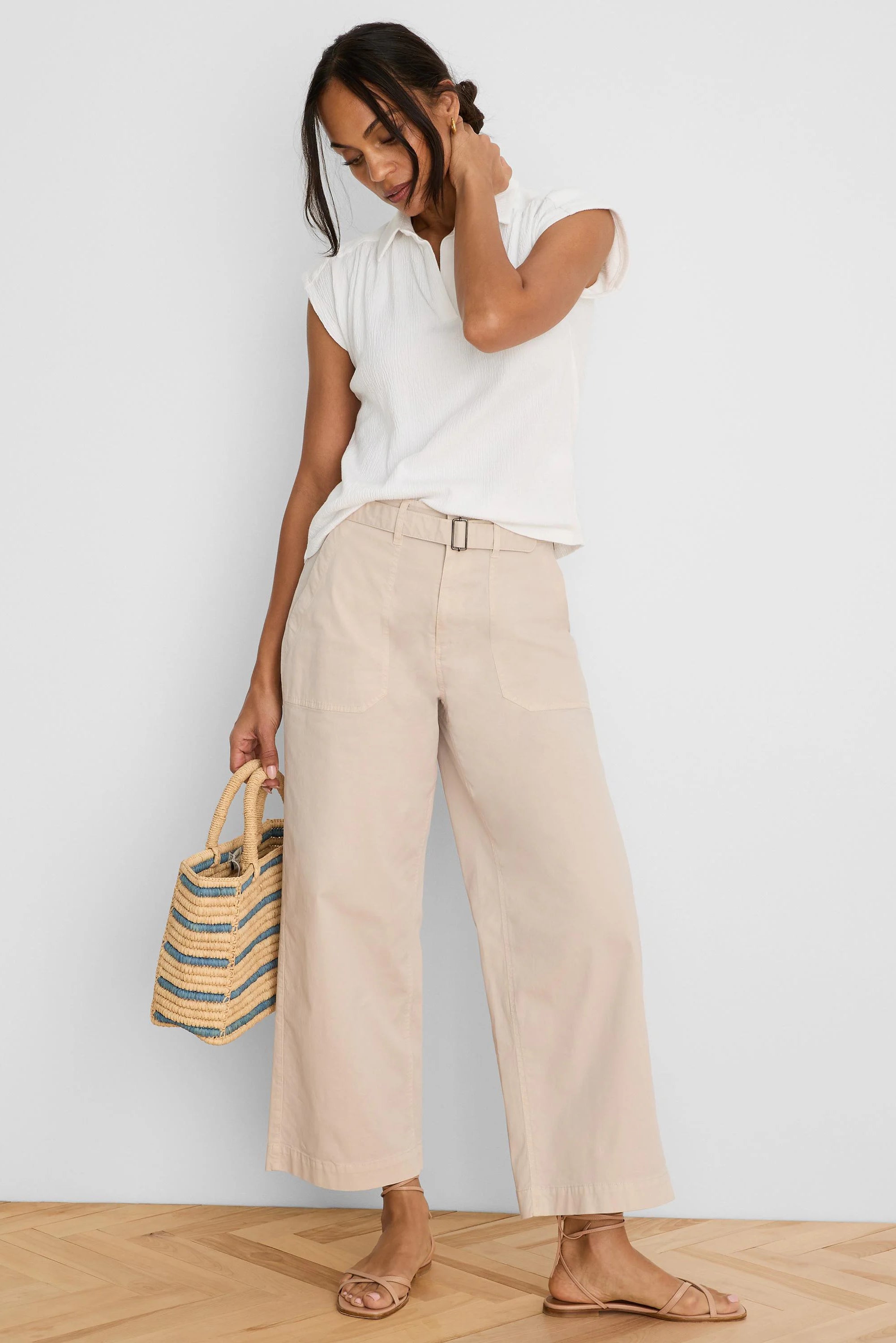 Pale beige wide-leg ankle pants with a self-belt, rectangular buckle, and front patch pockets.