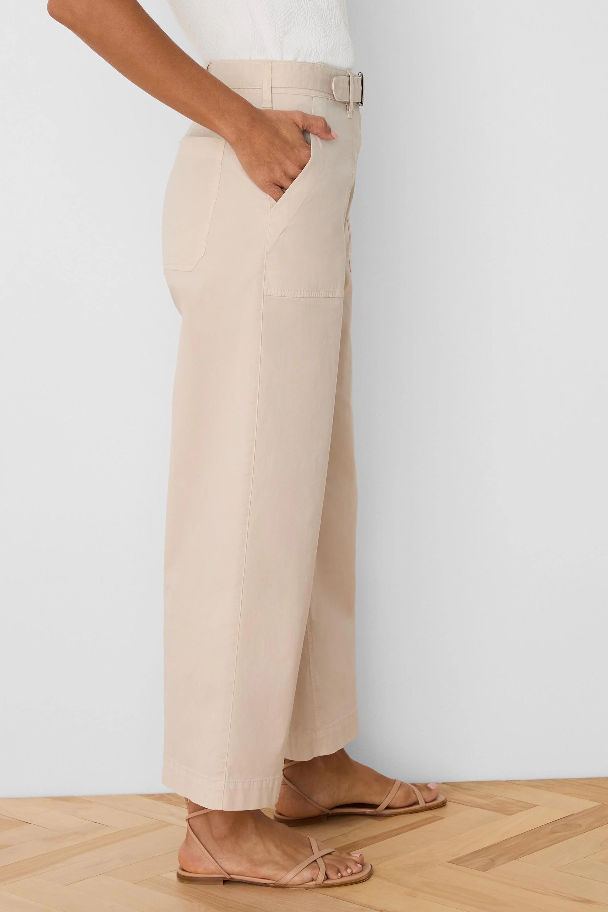Light beige wide-leg ankle pants with a D-ring belt and side pockets. Fabric appears soft.