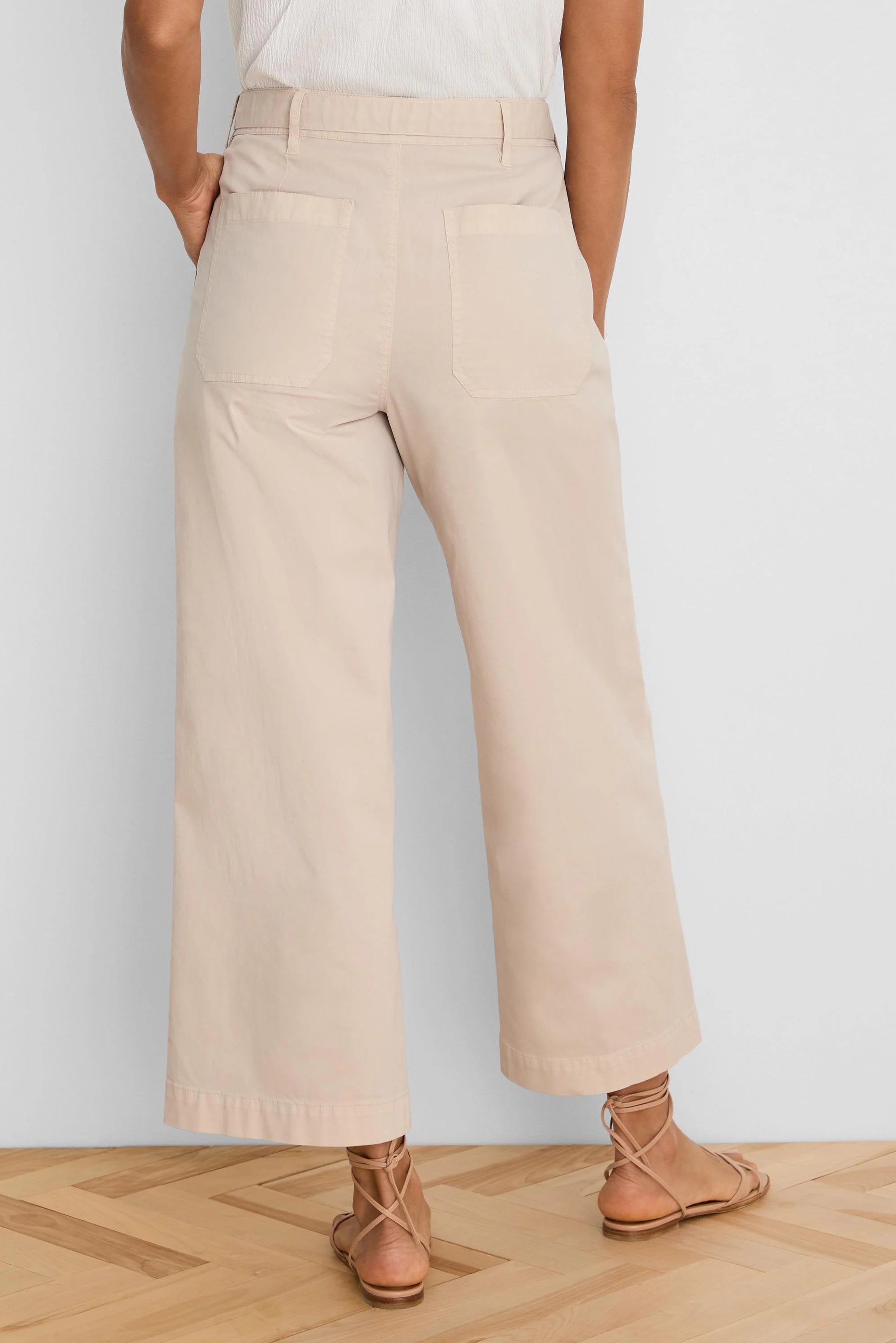 Light beige wide-leg ankle pants, shown from behind, with a high waist, belt loops, and two rear patch pockets.