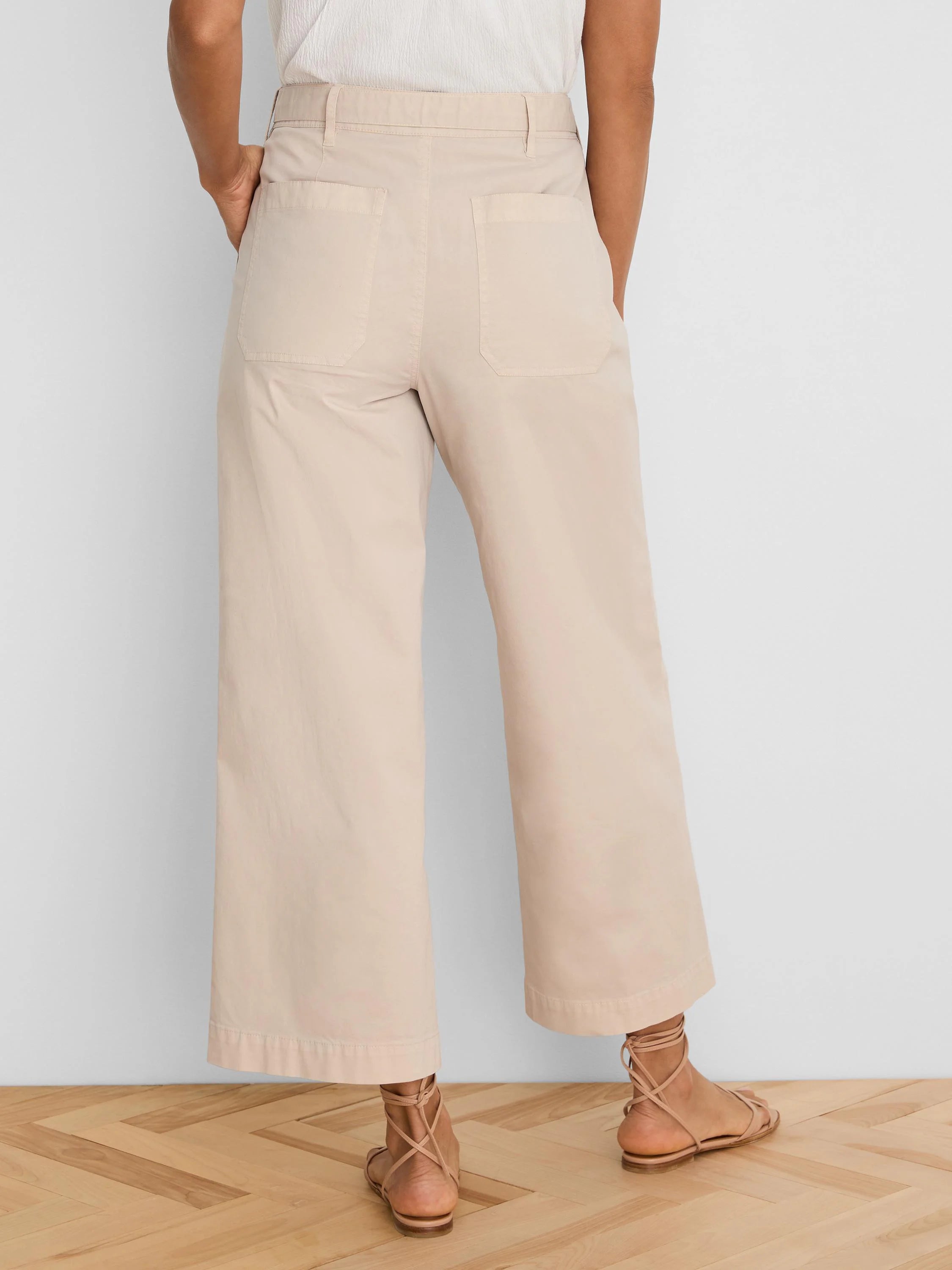 Light beige wide-leg ankle pants with back patch pockets and a waistband with belt loops.