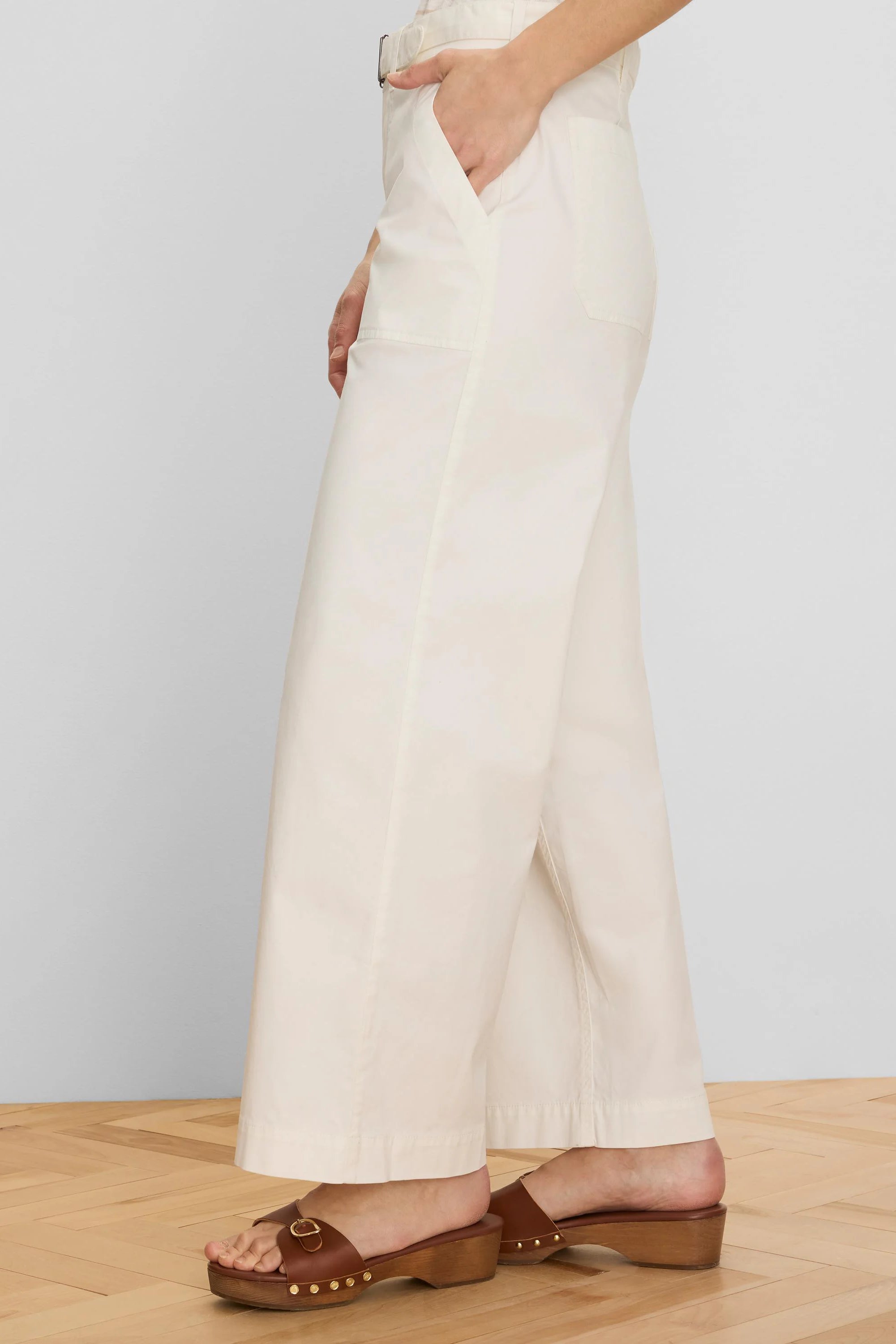 Cream wide-leg ankle pants with a matching belt and front slash pockets. Model's hand in pocket.