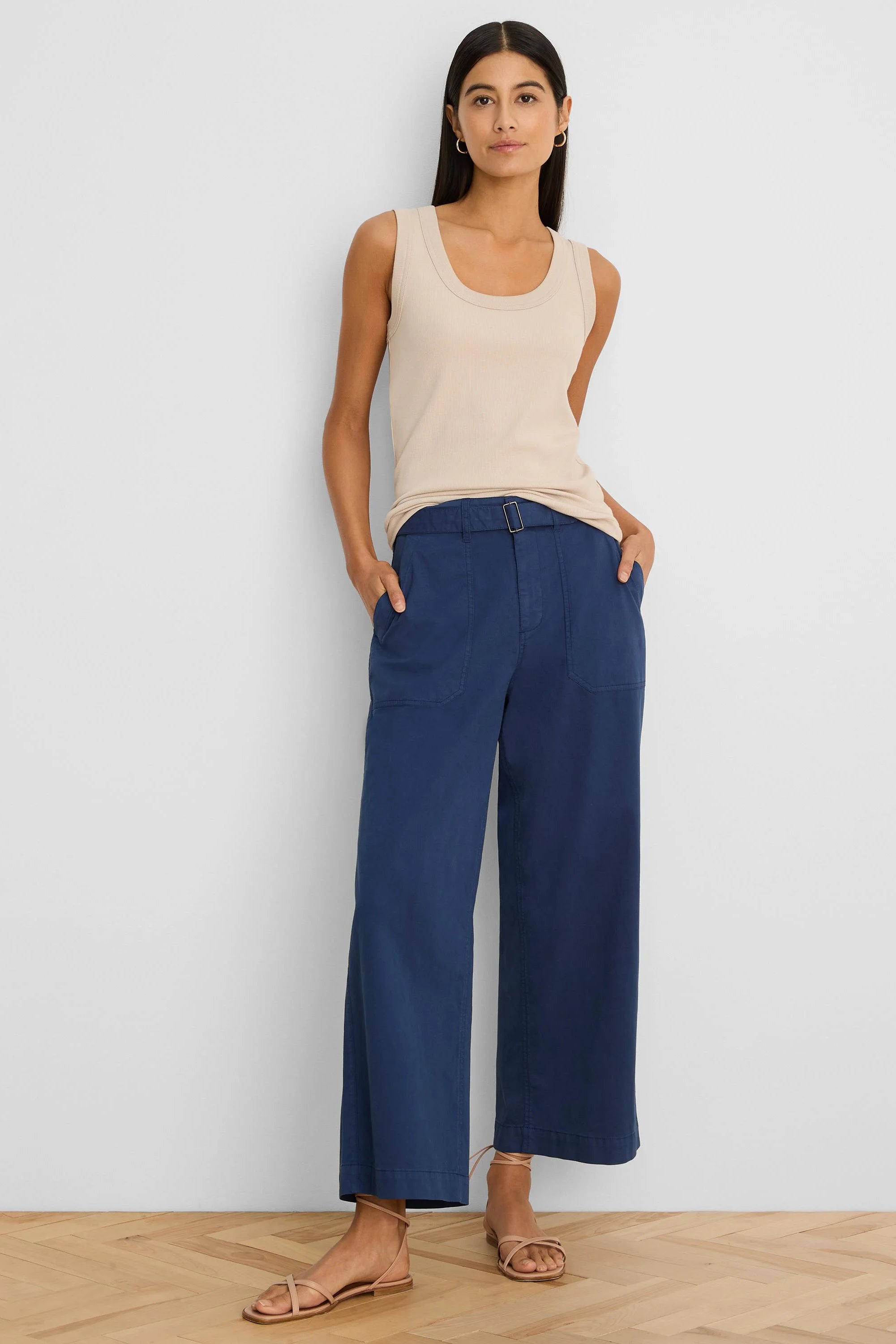 Dark blue wide-leg ankle pants with a belted waist, square silver buckle, and side pockets, worn by a model.