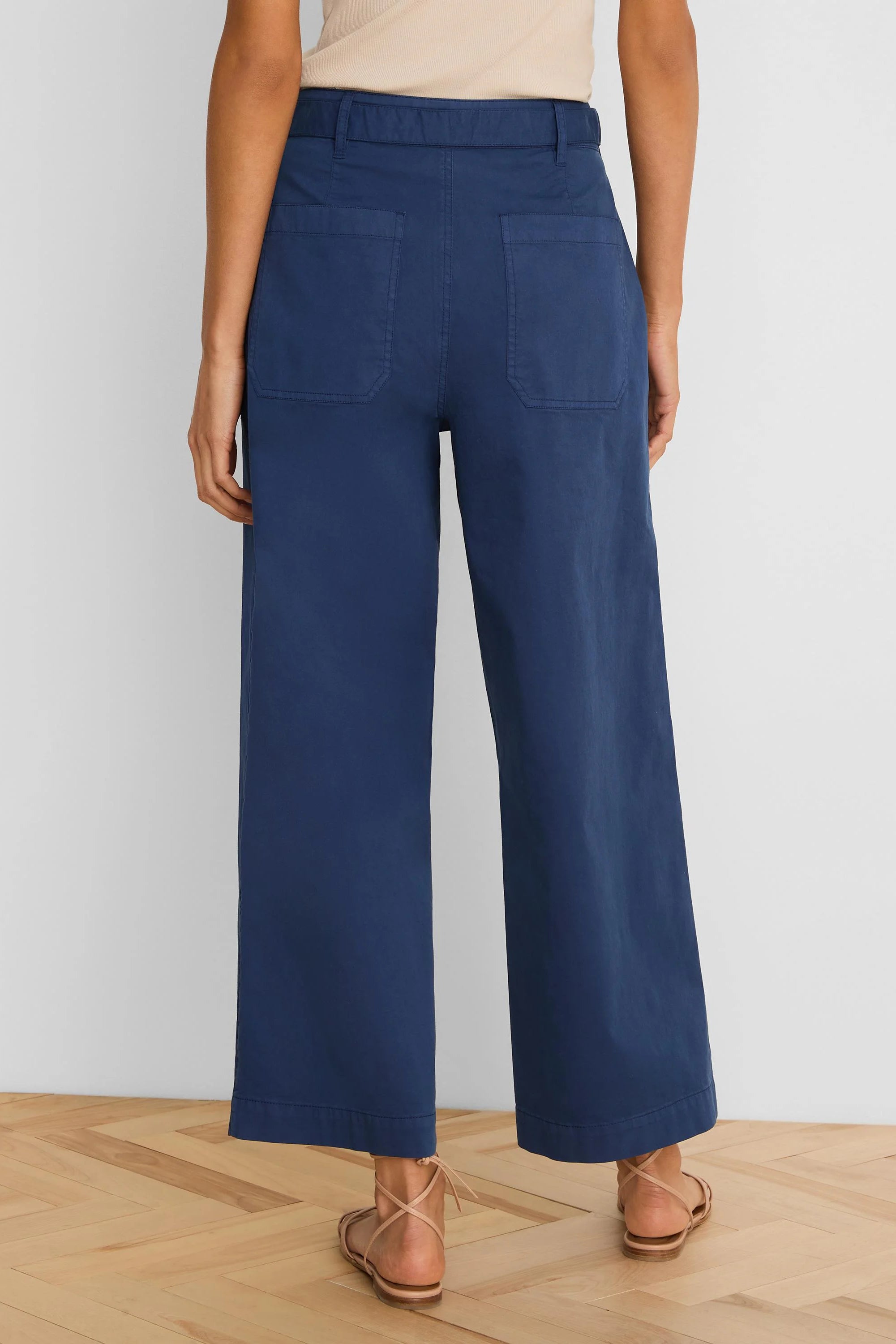 Dark blue wide-leg ankle pants with rear patch pockets and belt loops, shown from behind.