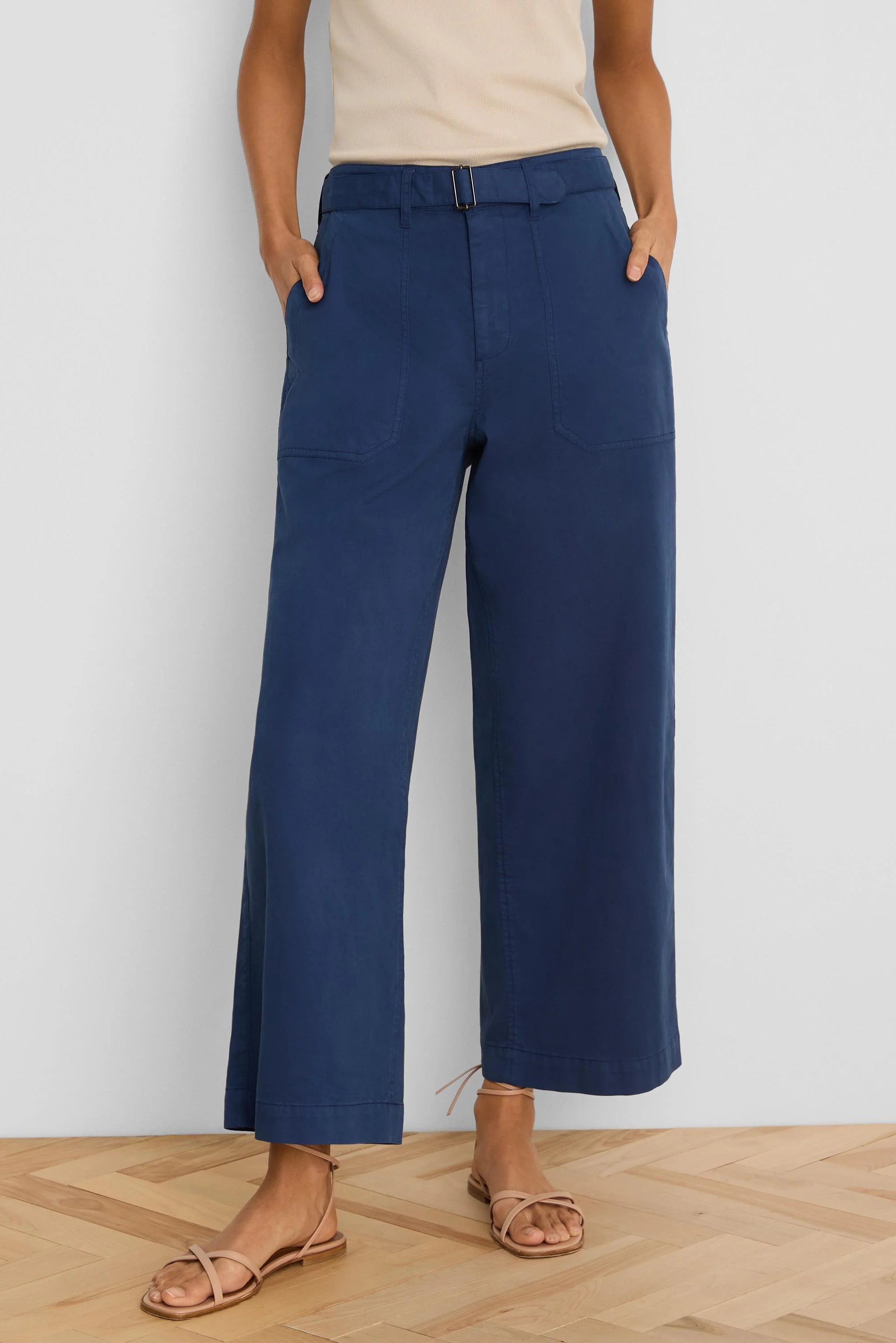 Dark blue wide-leg ankle pants with belted waist, front patch pockets, modeled on a person.