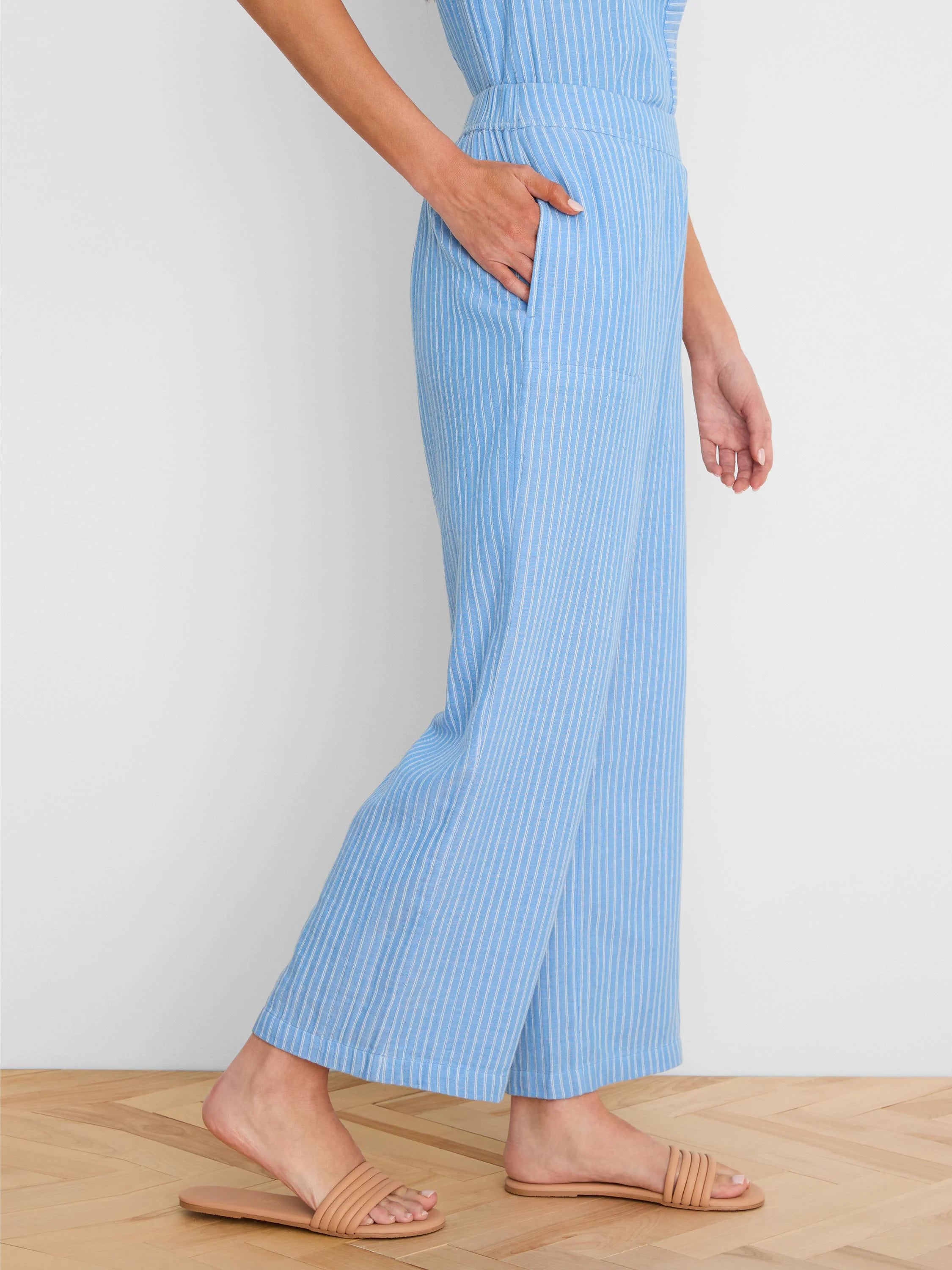 Light blue wide-leg gauze ankle pants with white vertical stripes. Model's hand in side pocket.