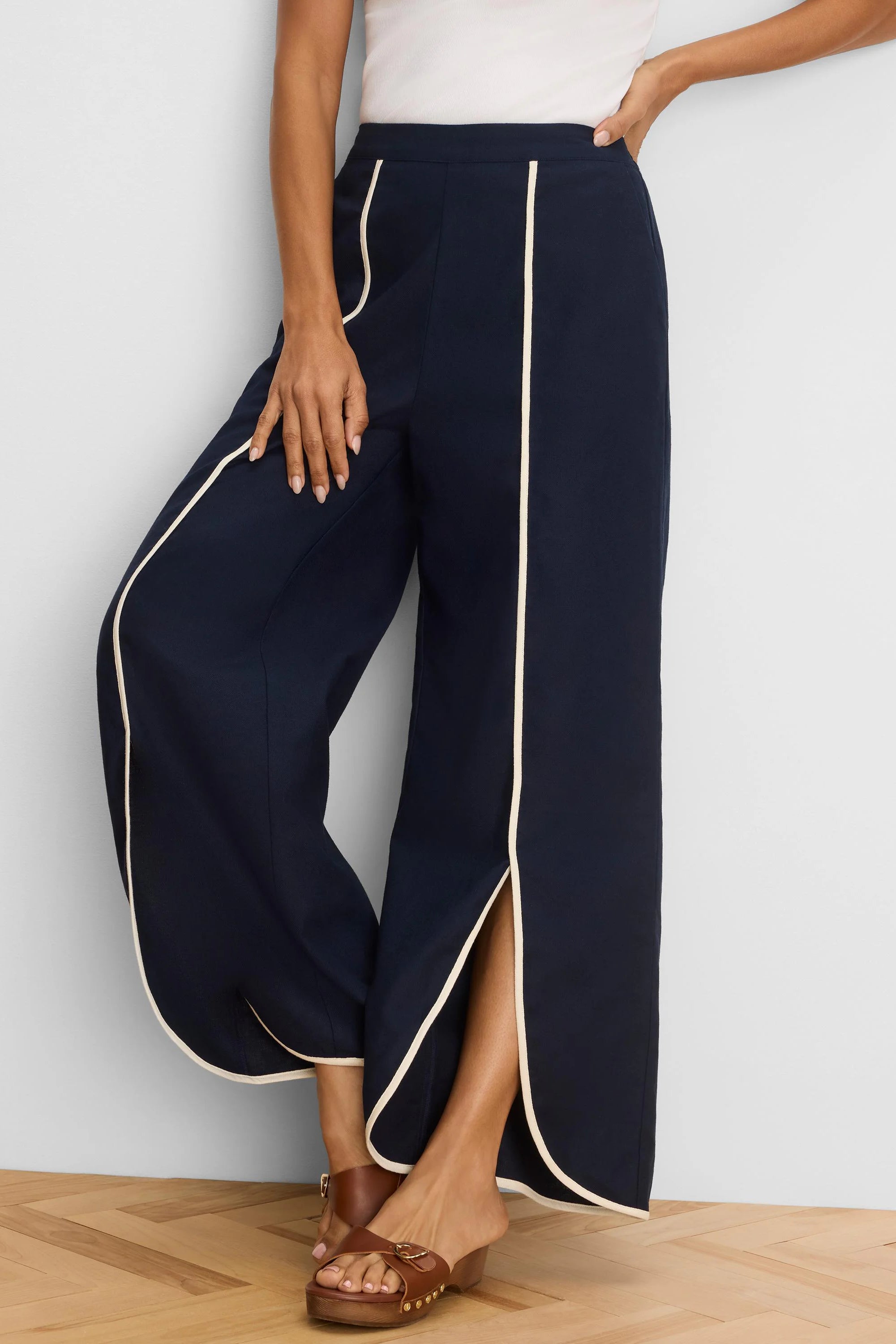 Navy wide leg pants with cream piping on outer seams, pockets, and a front split hem.