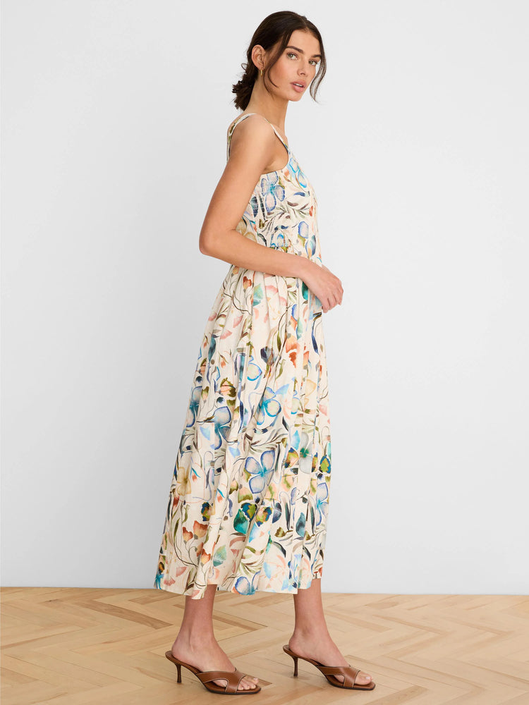 Cream midi dress with thin straps, smocked top, and a 'pressed flowers' print in blue, green, and orange.