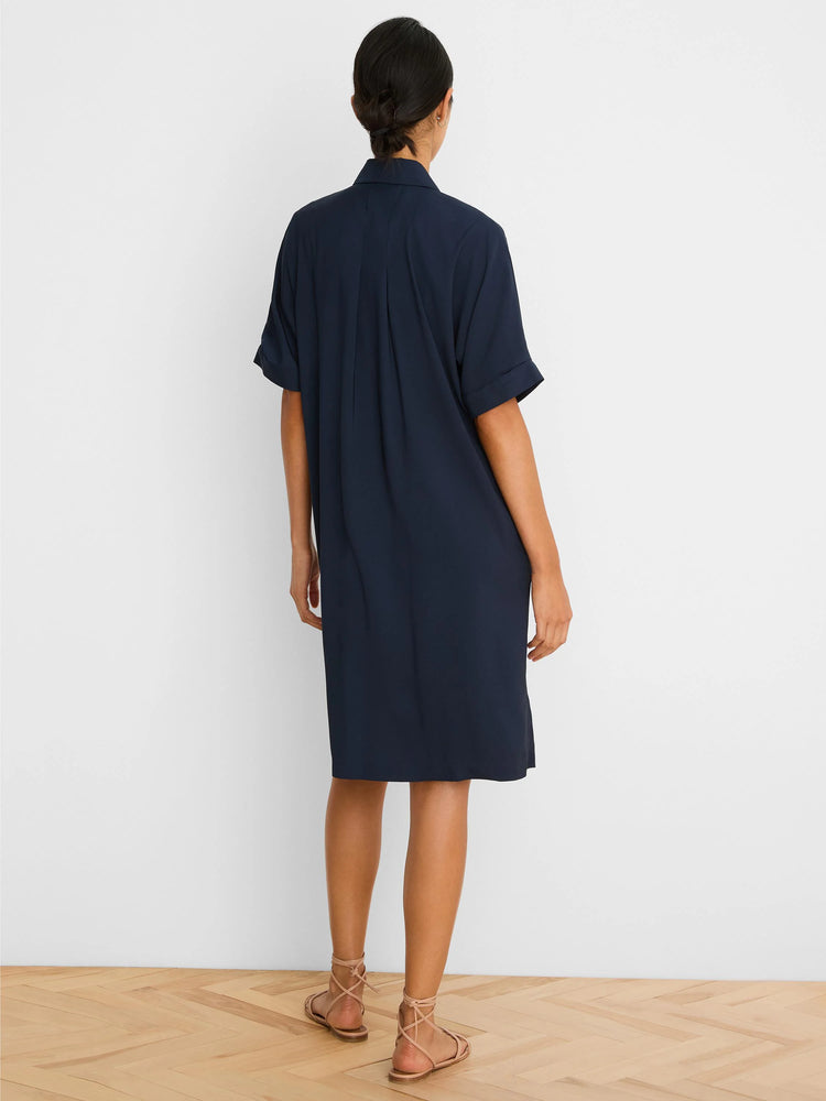 Navy button-down dress. Collared, with short cuffed sleeves, back pleats, and knee-length hem.