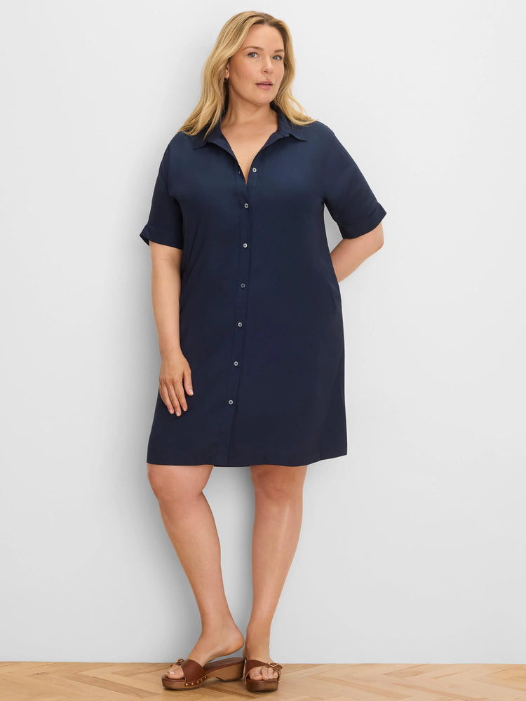 Navy button-down dress with a collar, light buttons, short cuffed sleeves, and side pockets. Modeled, above-knee length.