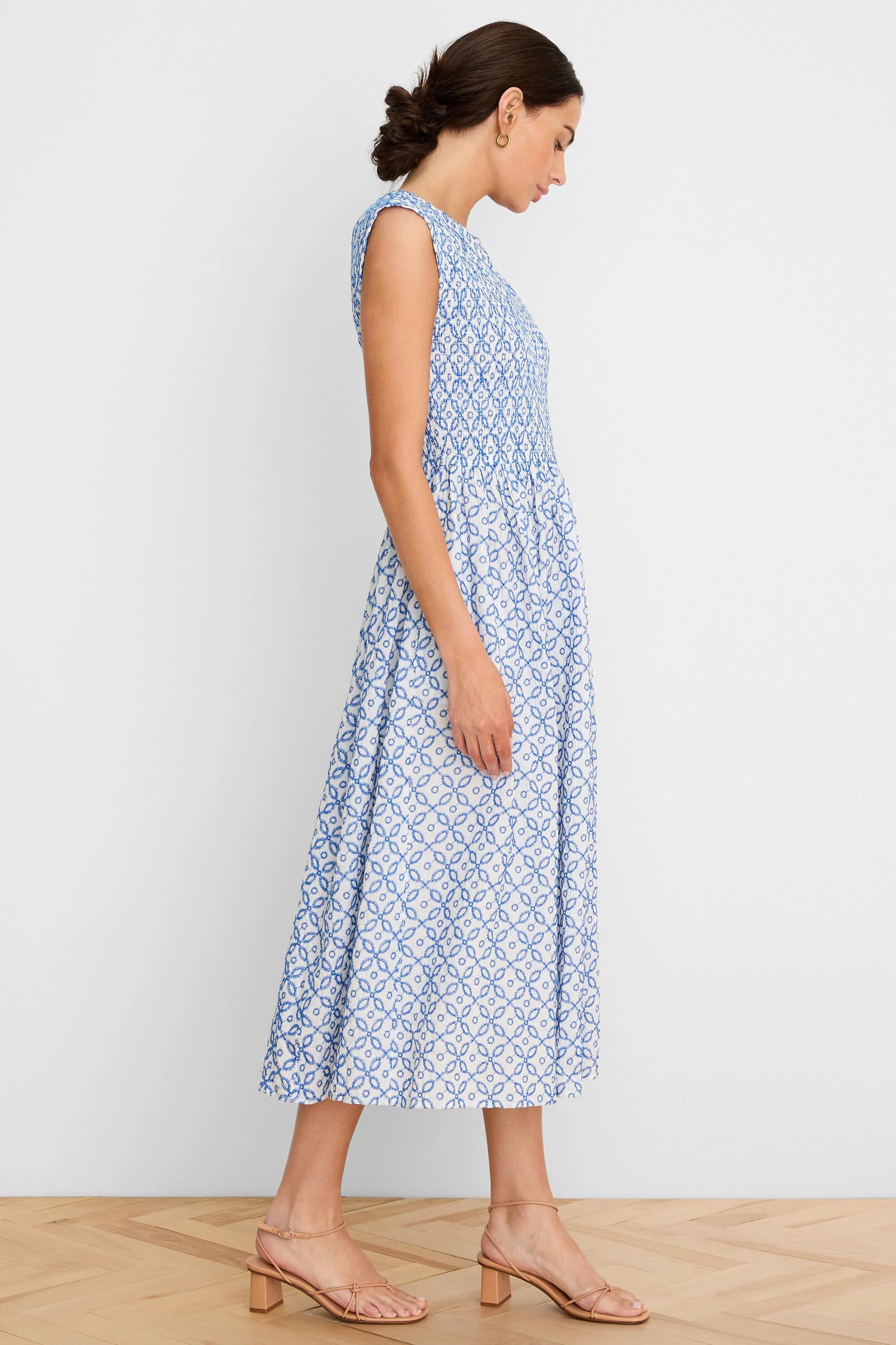 White midi dress with blue embroidered geometric tile pattern, sleeveless and smocked bodice.