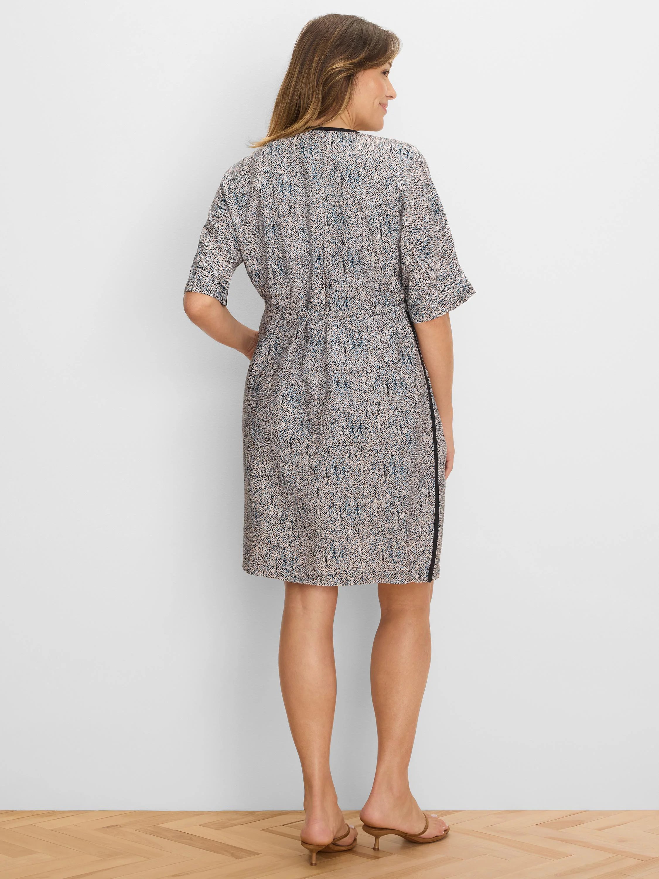 Light speckled dress with blue & black dots. Features black trim at neckline & side, short sleeves, and cinched waist.
