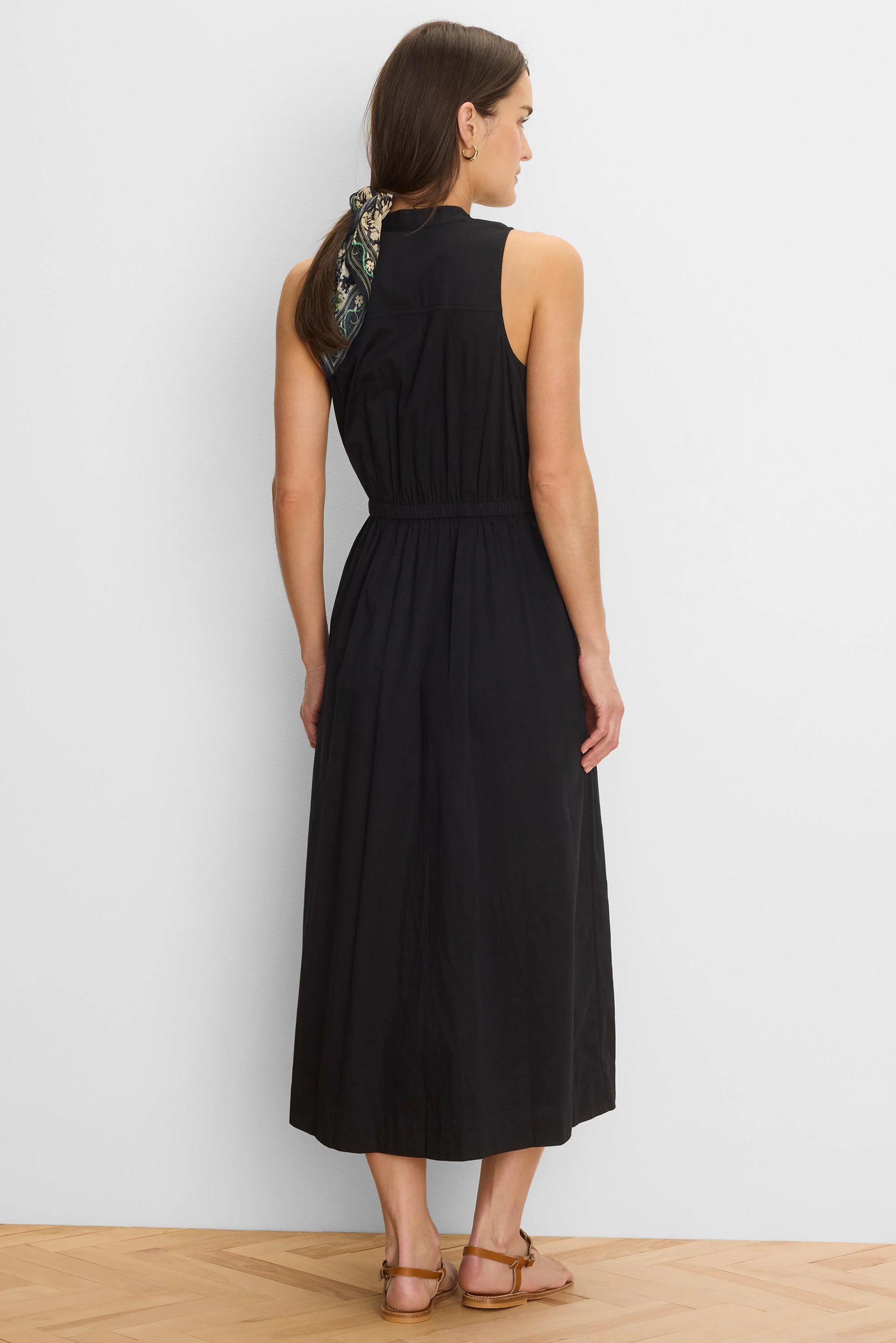 Black sleeveless midi dress with a high neck and elasticated waist, seen from the back.
