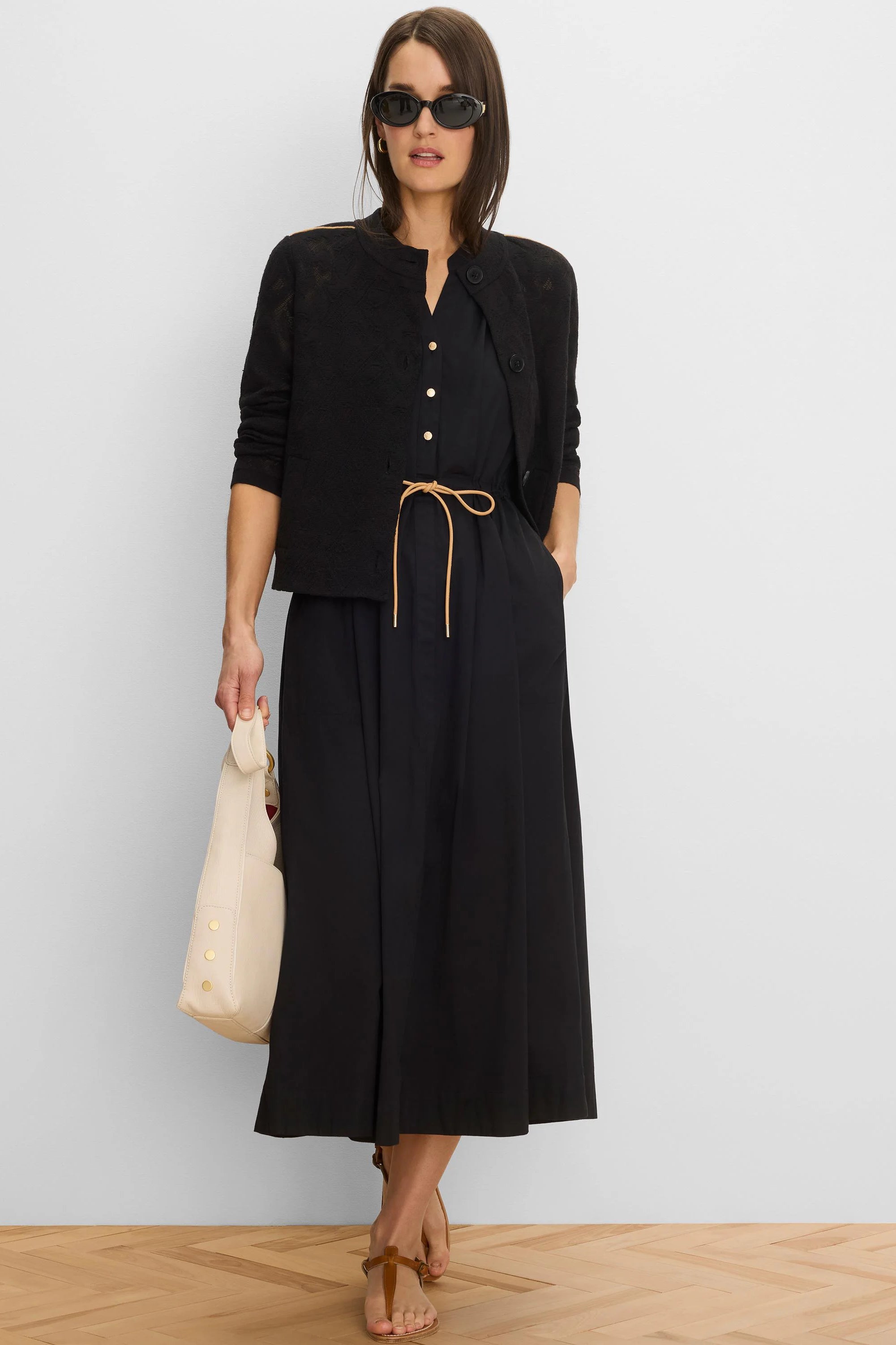 Black midi-length dress with a V-neck, golden front buttons, and a tan drawstring waist.