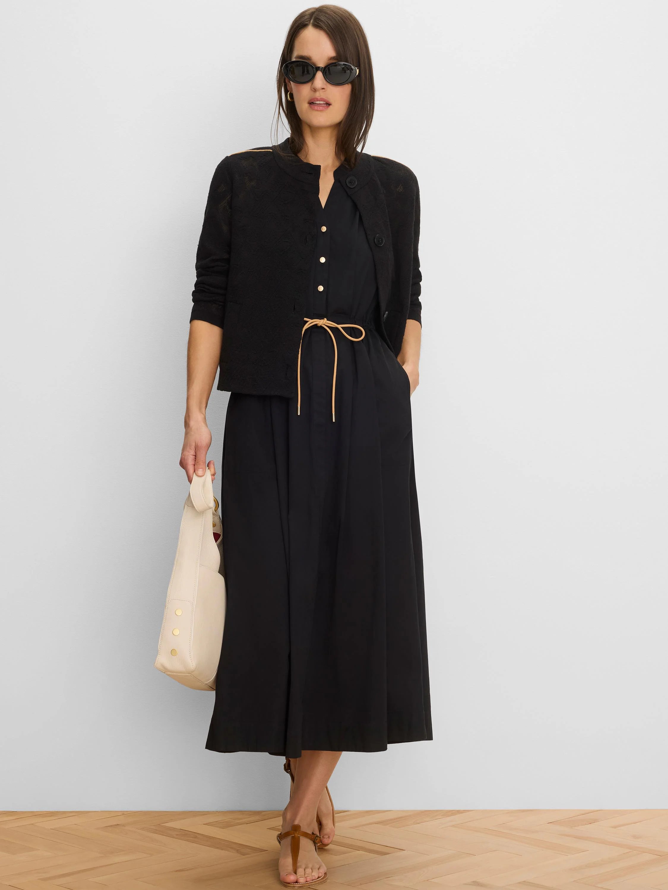 Black midi-length dress with a V-neck, golden front buttons, and a tan drawstring waist.