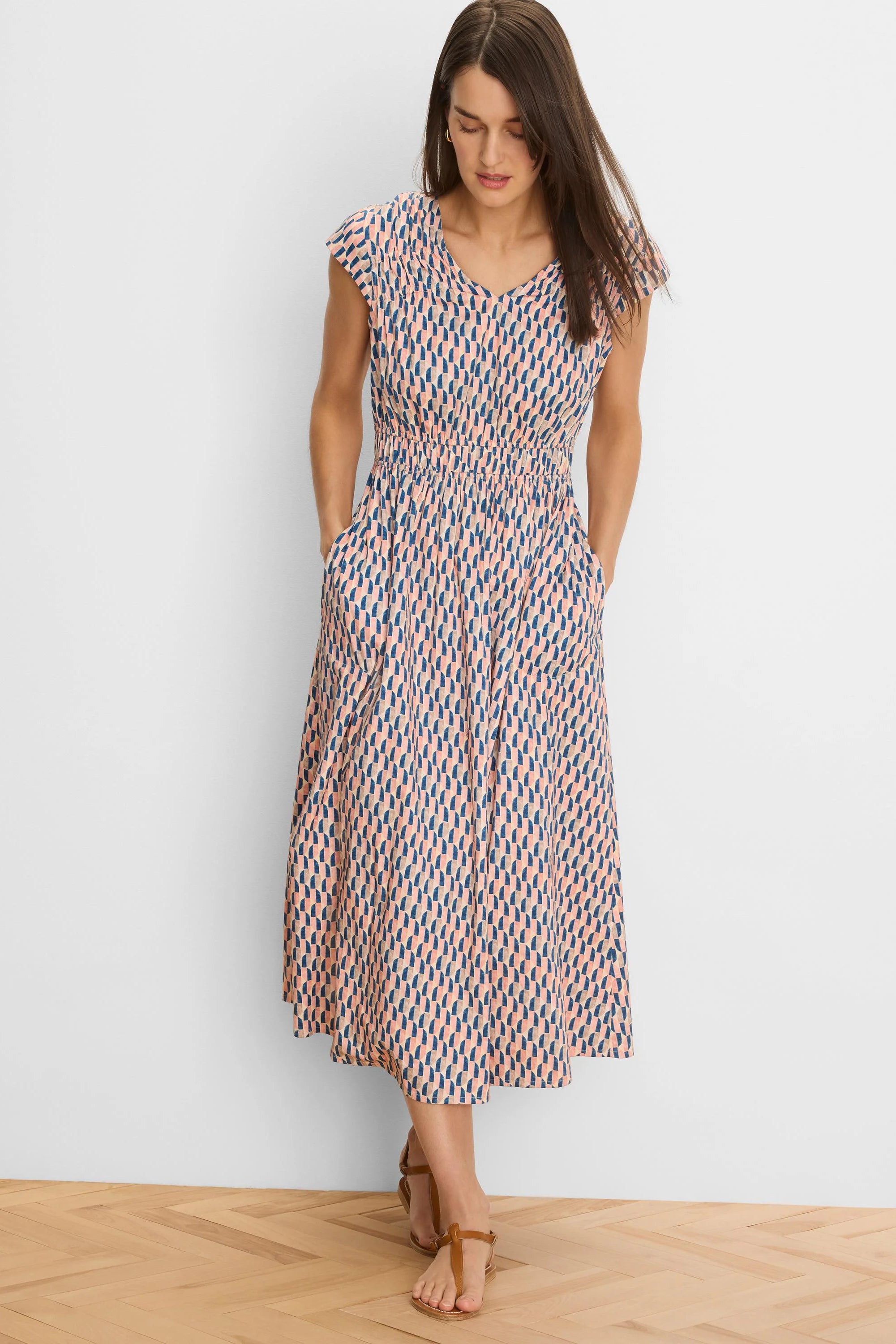 Cap sleeve V-neck midi dress with peach and navy geometric print, shirred waist, and pockets.