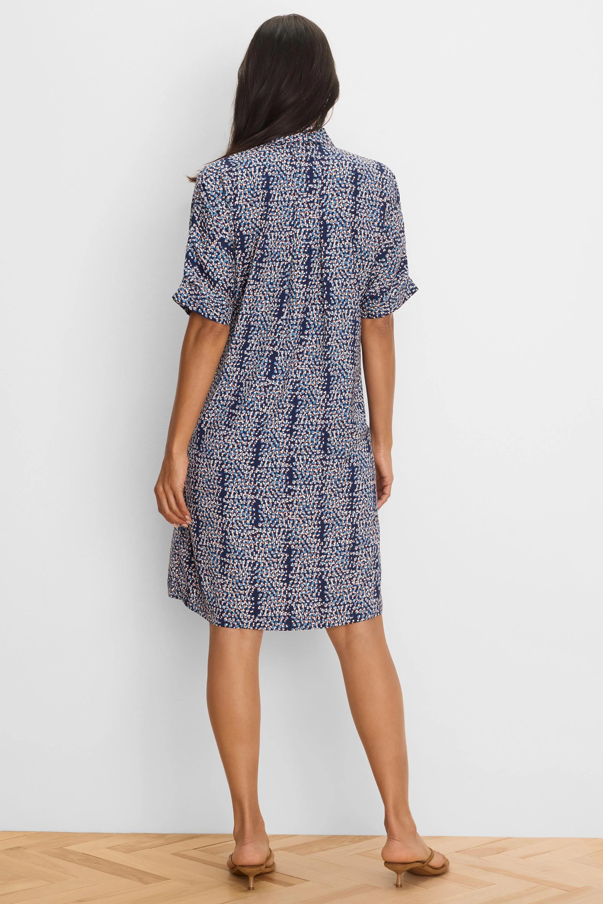 Navy shirt dress with blue, white, peach speckled pattern, cuffed short sleeves, above-knee. Shown from back.