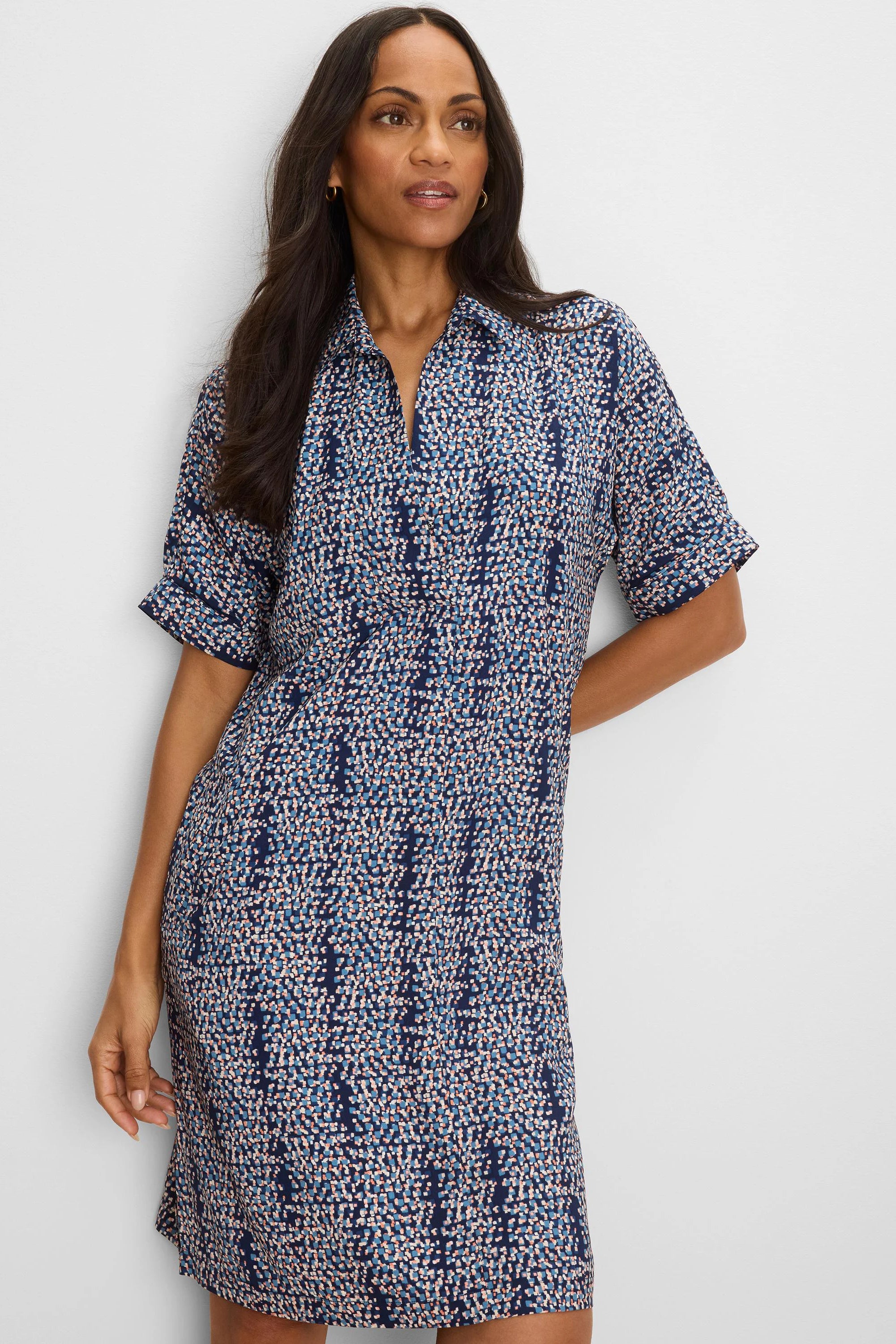 Navy blue shift dress with short cuffed sleeves, collared V-neck, and a scattered square print in light blue, peach, and...