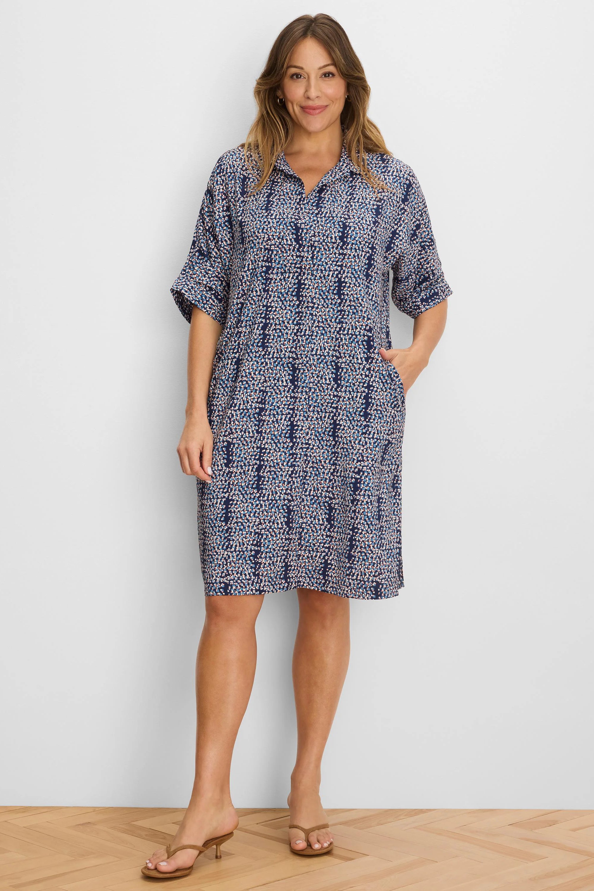 Navy dress with light blue, white, coral pixel pattern. V-neck, cuffed short sleeves, knee-length, pockets.