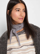 Soft grey knit mini scarf tied in a simple knot around the neck.