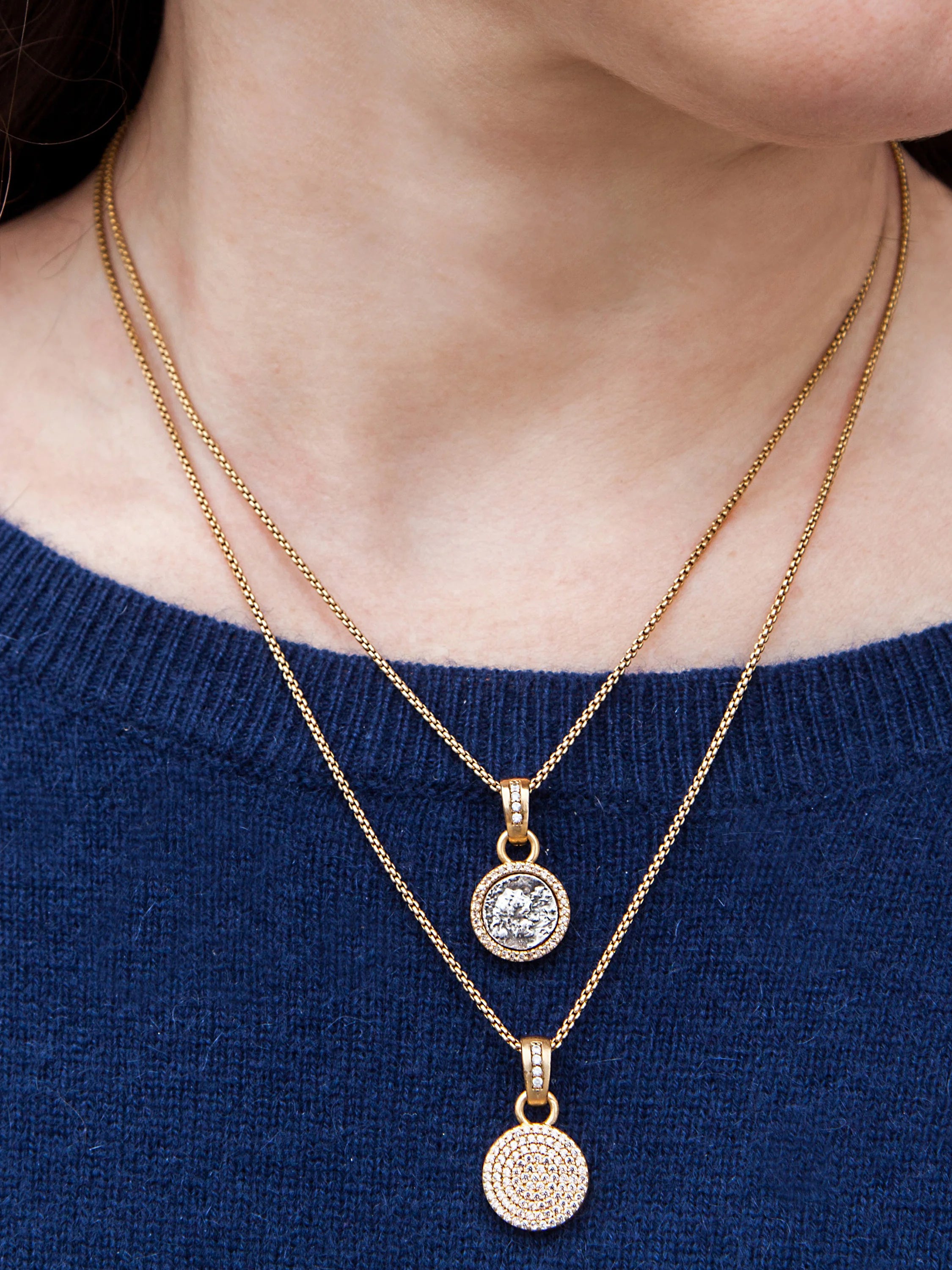 Gold necklace with two circular pendants. Larger pendant features a grey coin-like center, smaller pendant is fully...