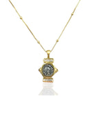 Gold beaded chain necklace. Pendant features a central textured dark gray coin, framed by gold and clear stones.