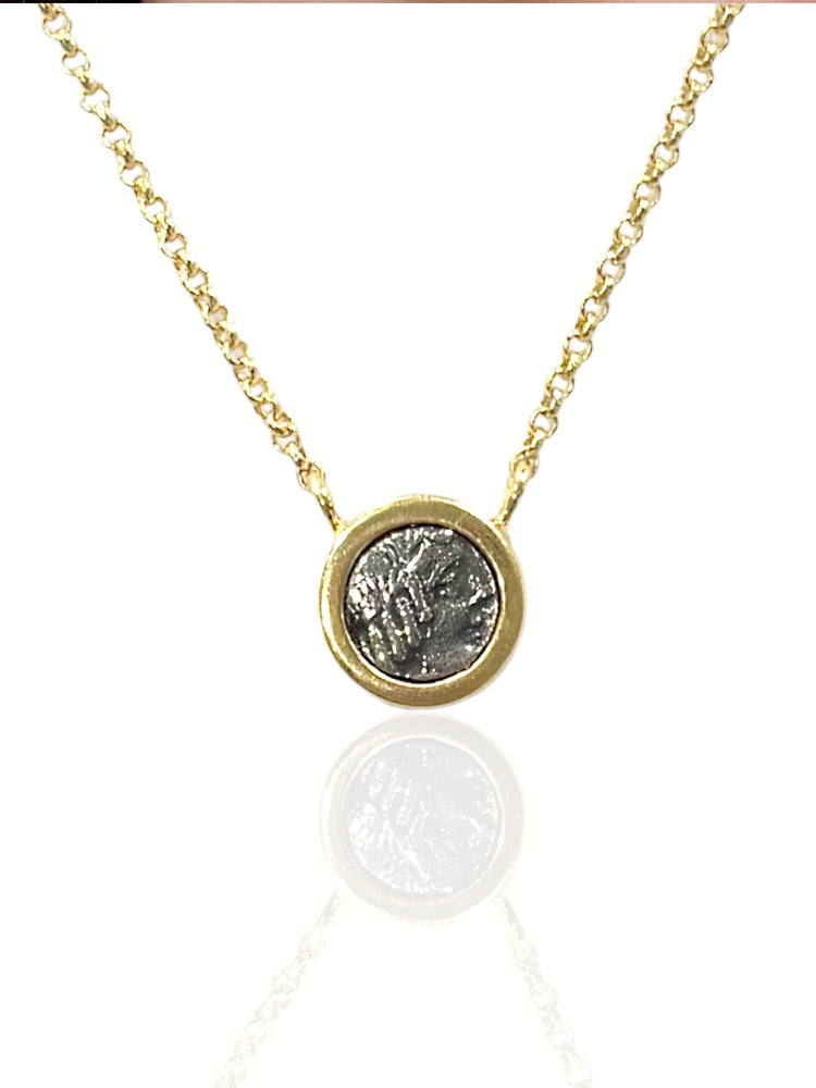 Gold chain necklace with a circular, gray coin-like pendant in a gold frame.