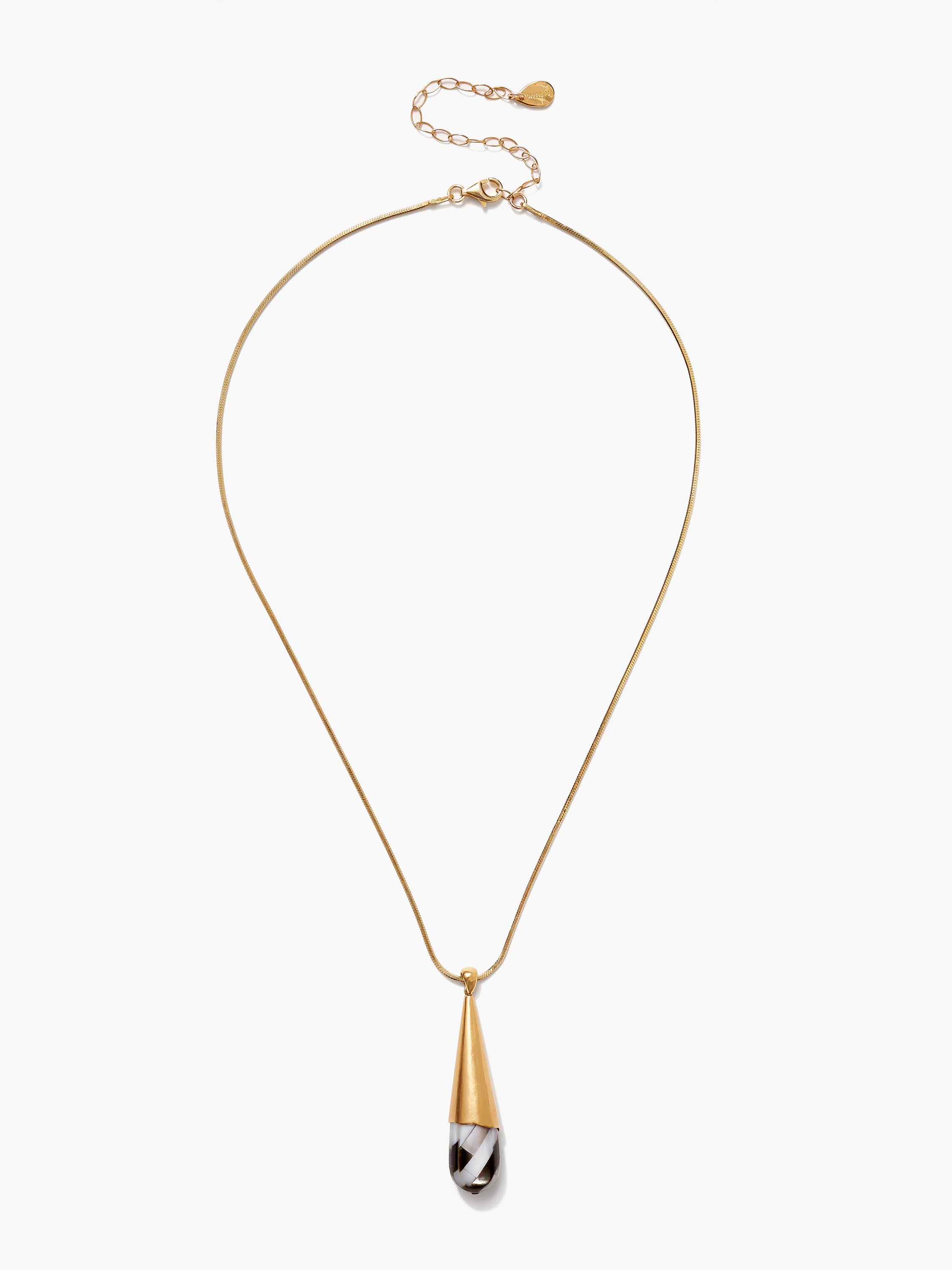 Gold snake chain necklace with a pendant: a conical gold top over a black and white patterned mother-of-pearl drop.
