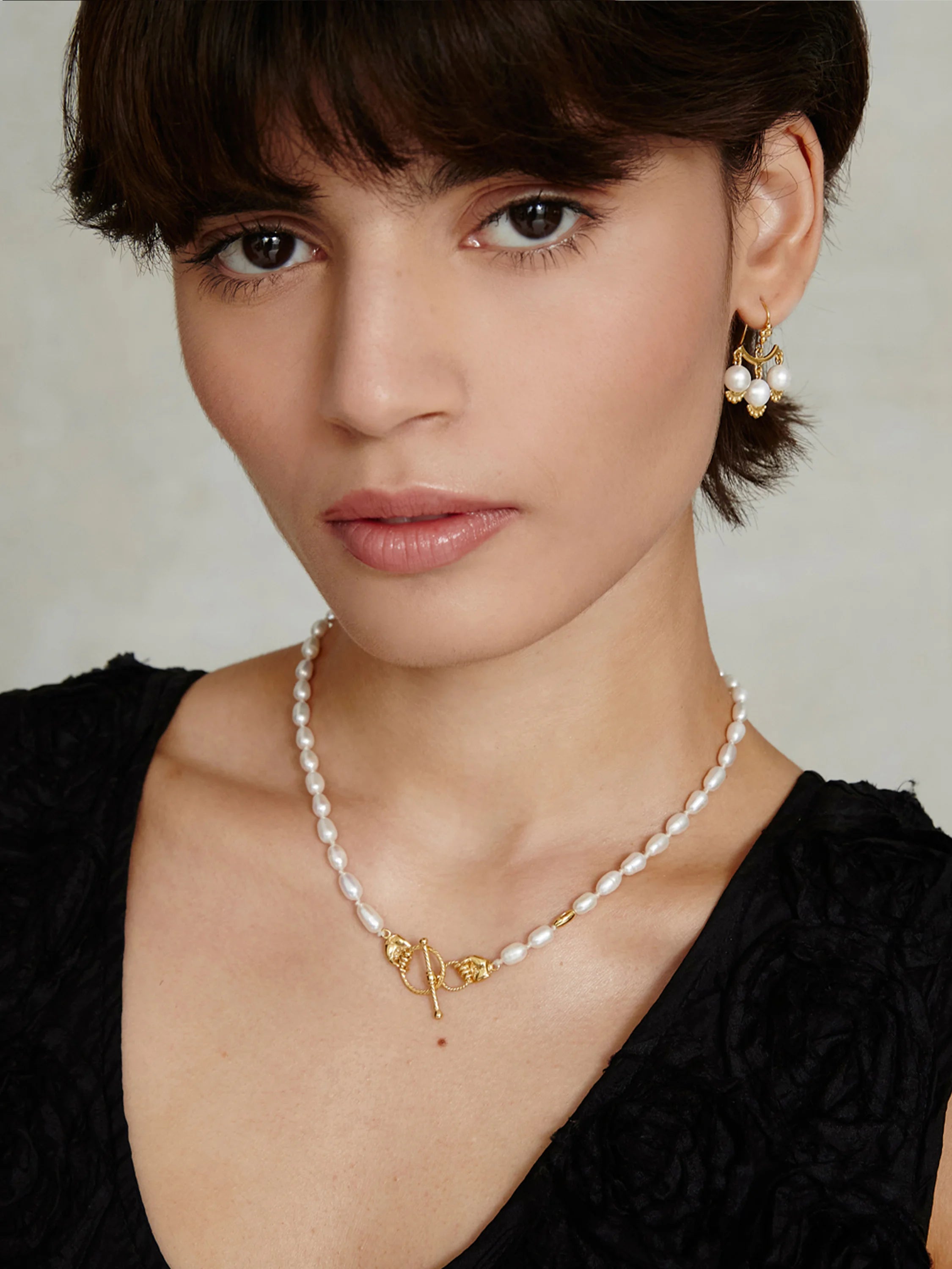 White baroque pearl necklace with a visible gold toggle clasp.