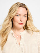 Gold chain necklace with a single, light pink, irregular drop pearl, shown worn by a model.