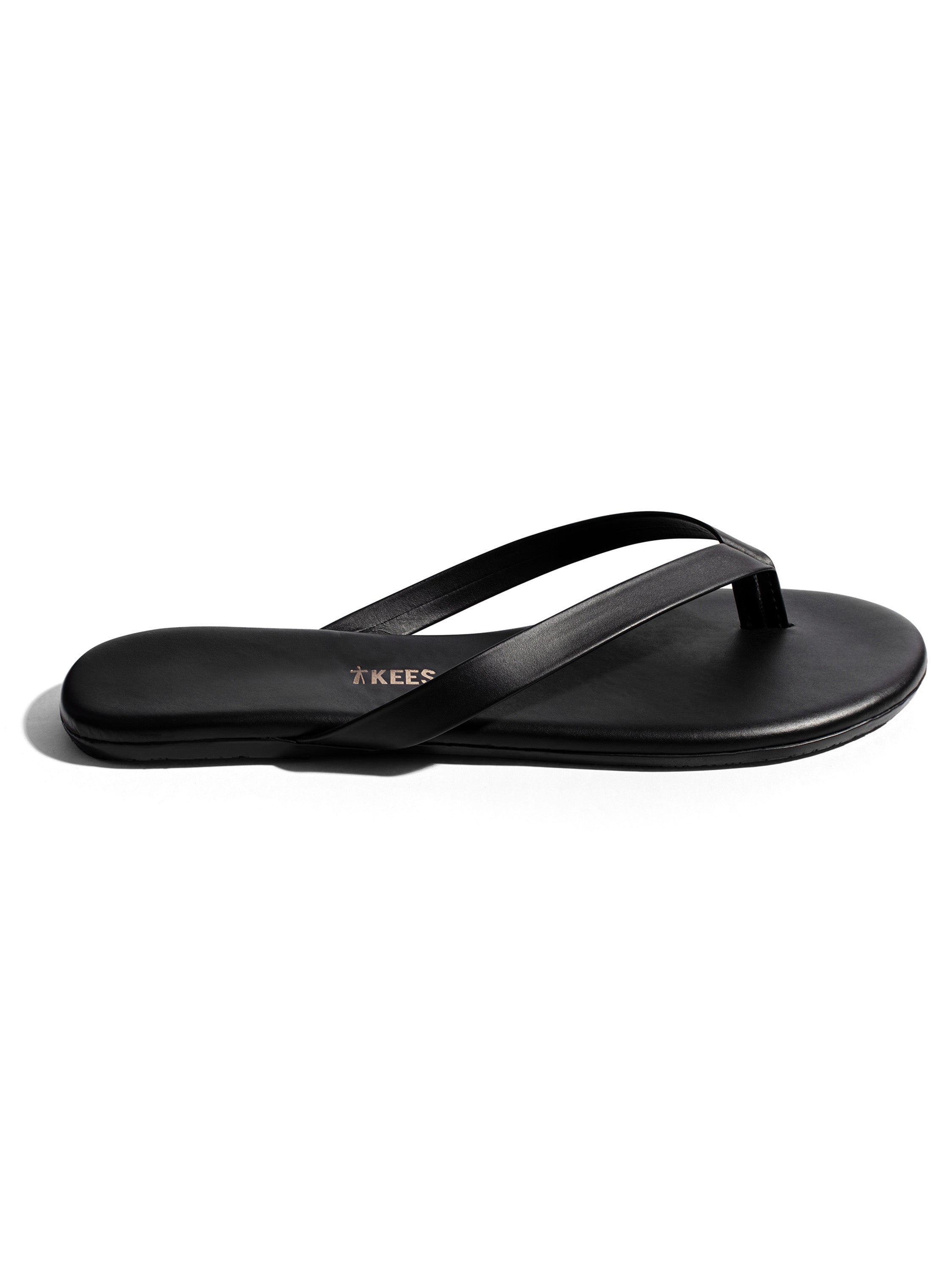 These black leather minimalist thong sandals feature a flat sole and thin, narrow crossover straps.