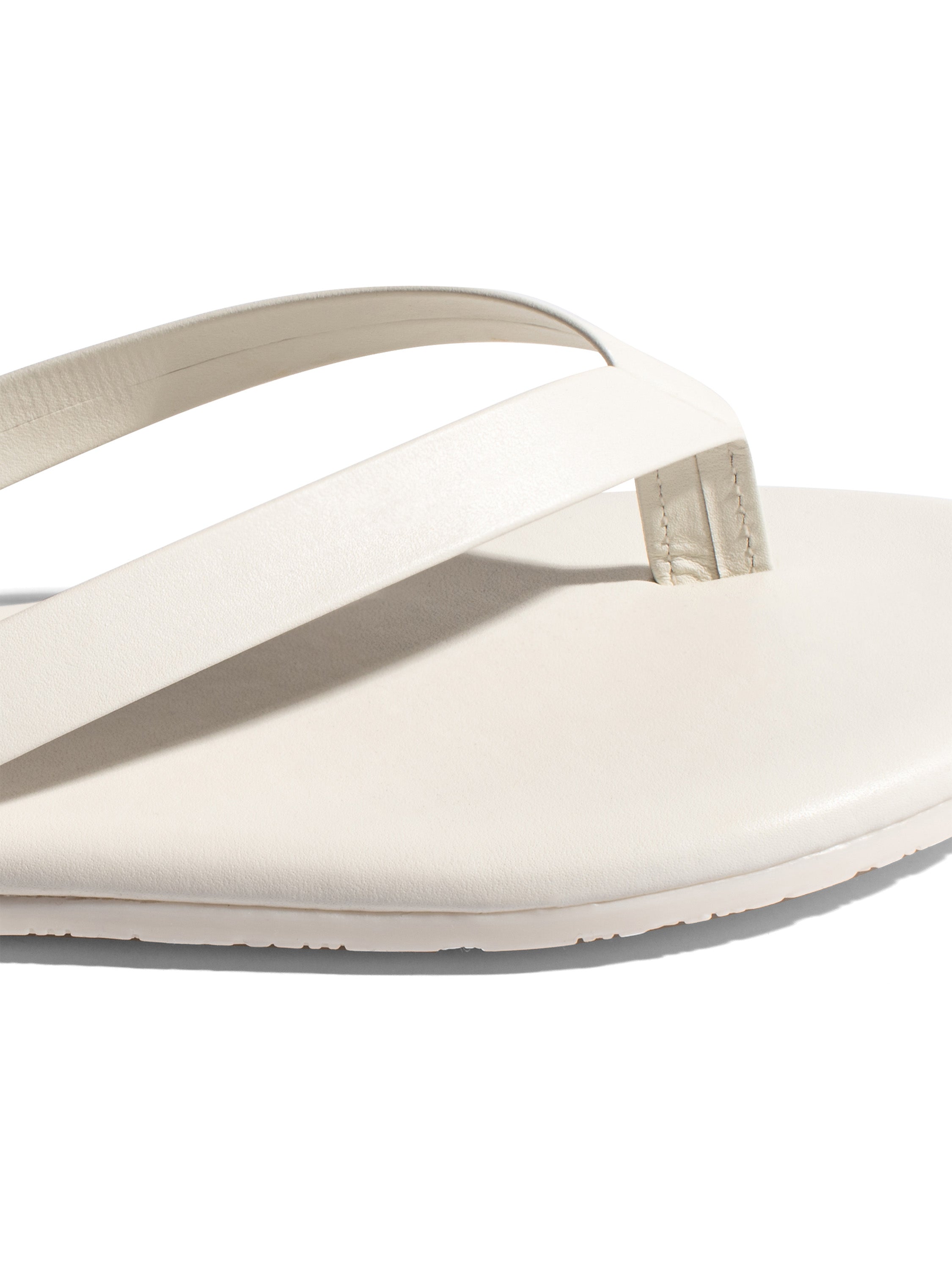 Minimalist off-white leather flip-flop featuring a flat sole and streamlined straps for a modern, casual look.