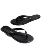 Pair of black flip-flops with thin straps and a gold TKEES logo on the insole, shown on a white background.