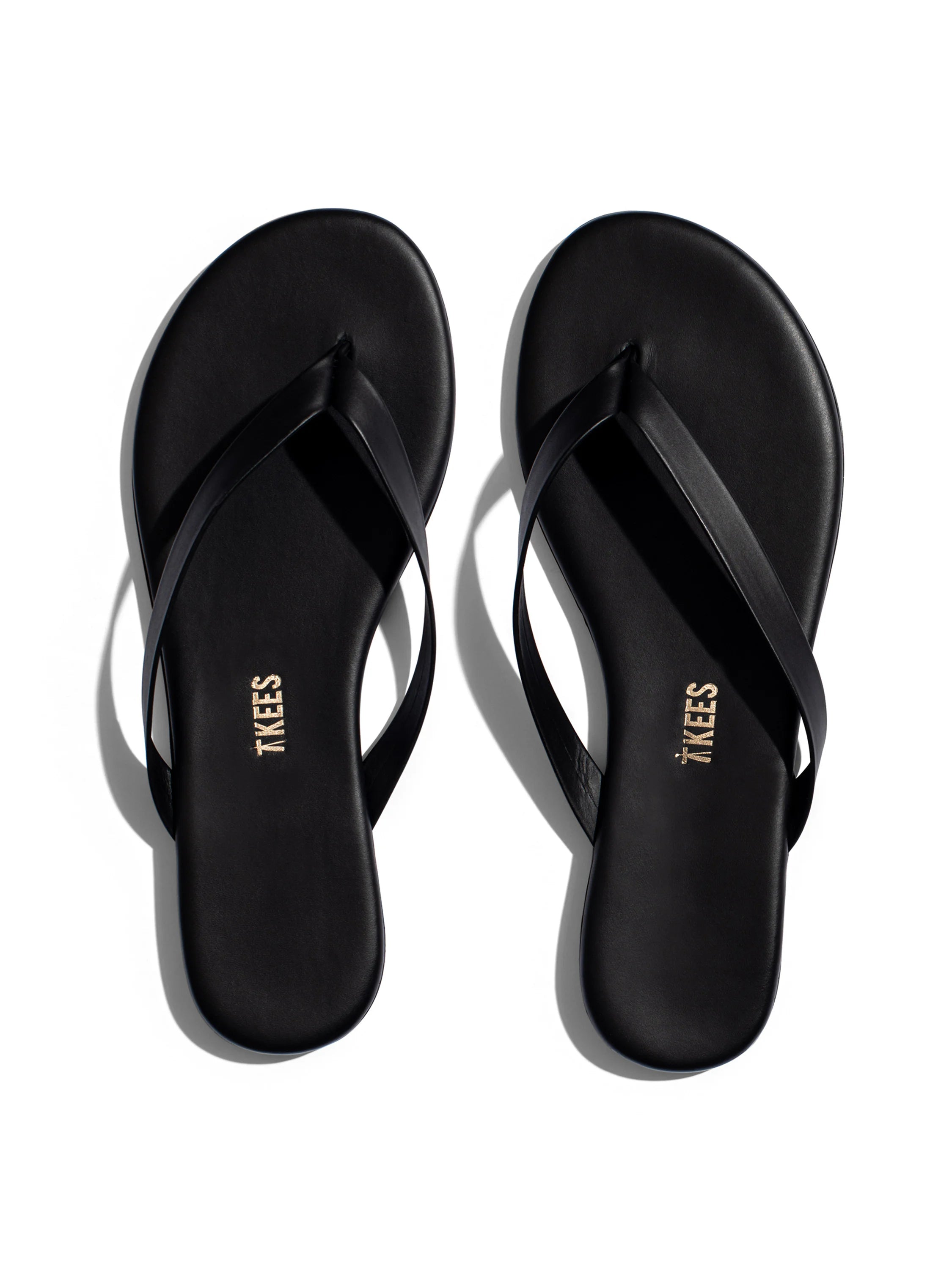 Pair of black leather thong sandals;  gold "TKEES" logo on soles.
