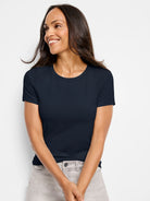 A woman wears a dark blue, fitted, short-sleeve crew neck tee.