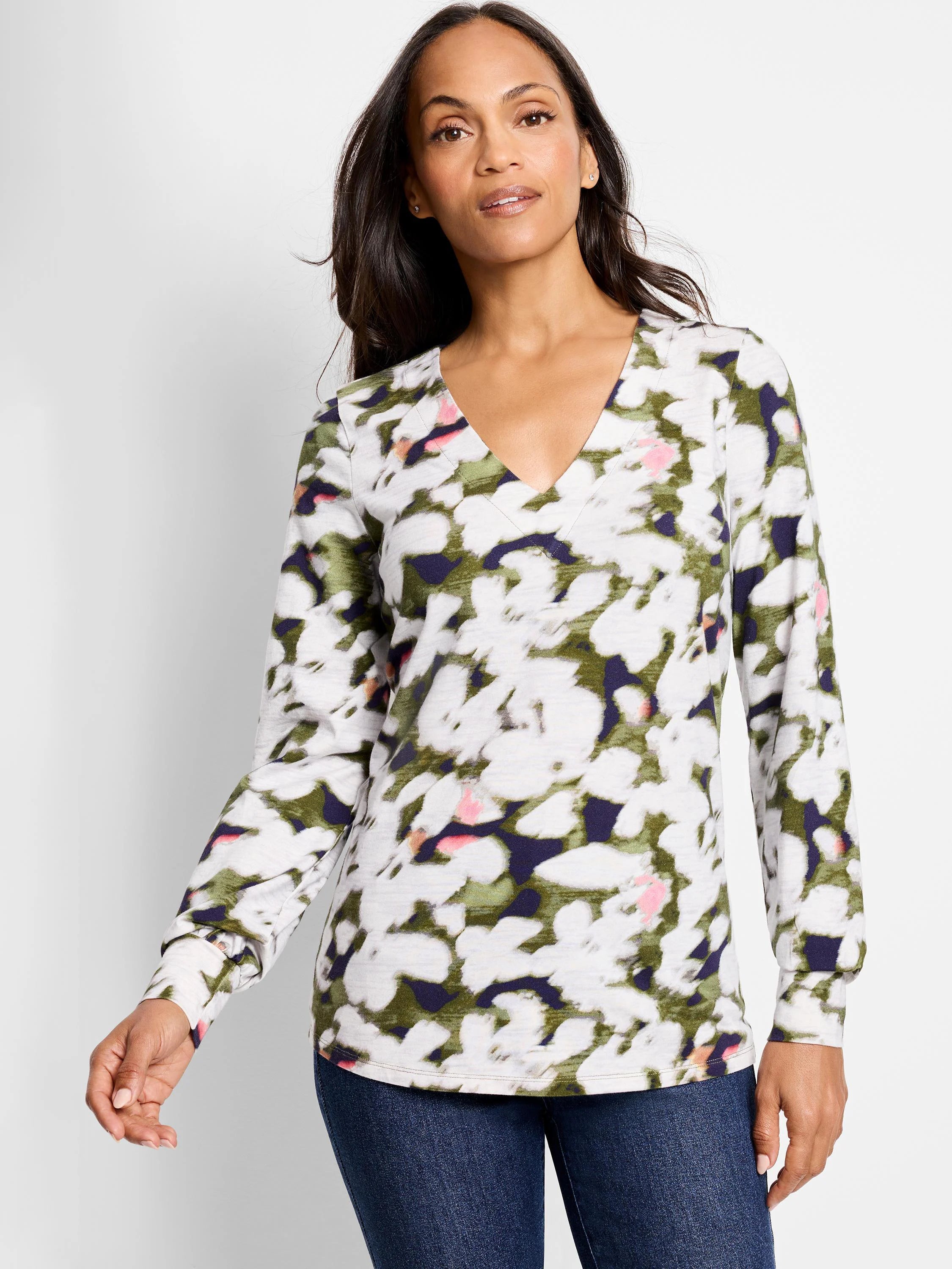Long-sleeve v-neck top. Off-white background with blurred olive green, dark purple, and pink petal-like pattern.