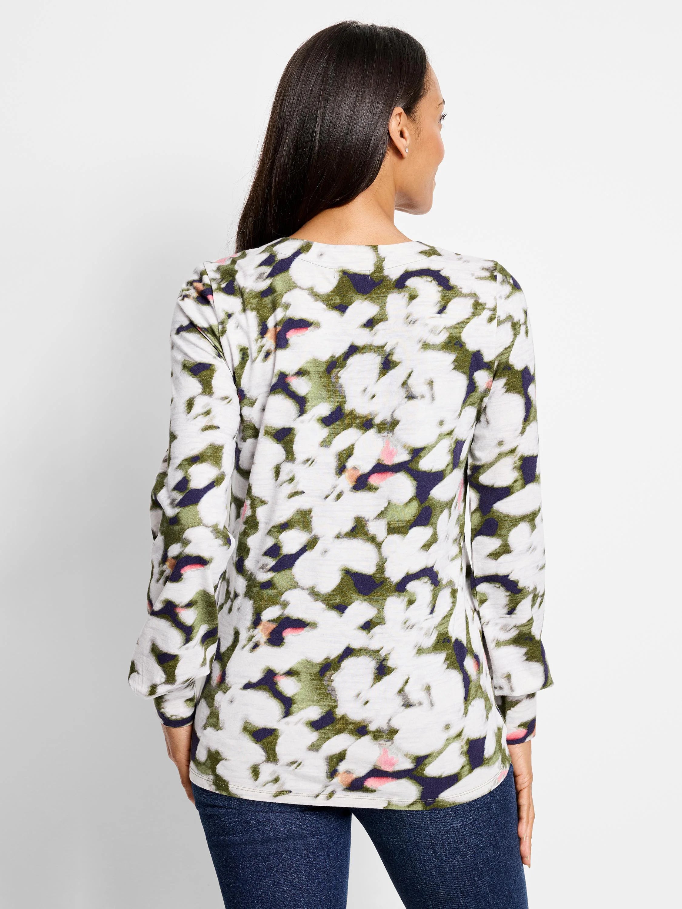 Long-sleeve top, white background with blurred olive green, dark purple, and pink floral print. Long sleeves.