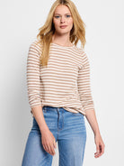 Beige and white horizontal striped long-sleeve boat neck shirt.