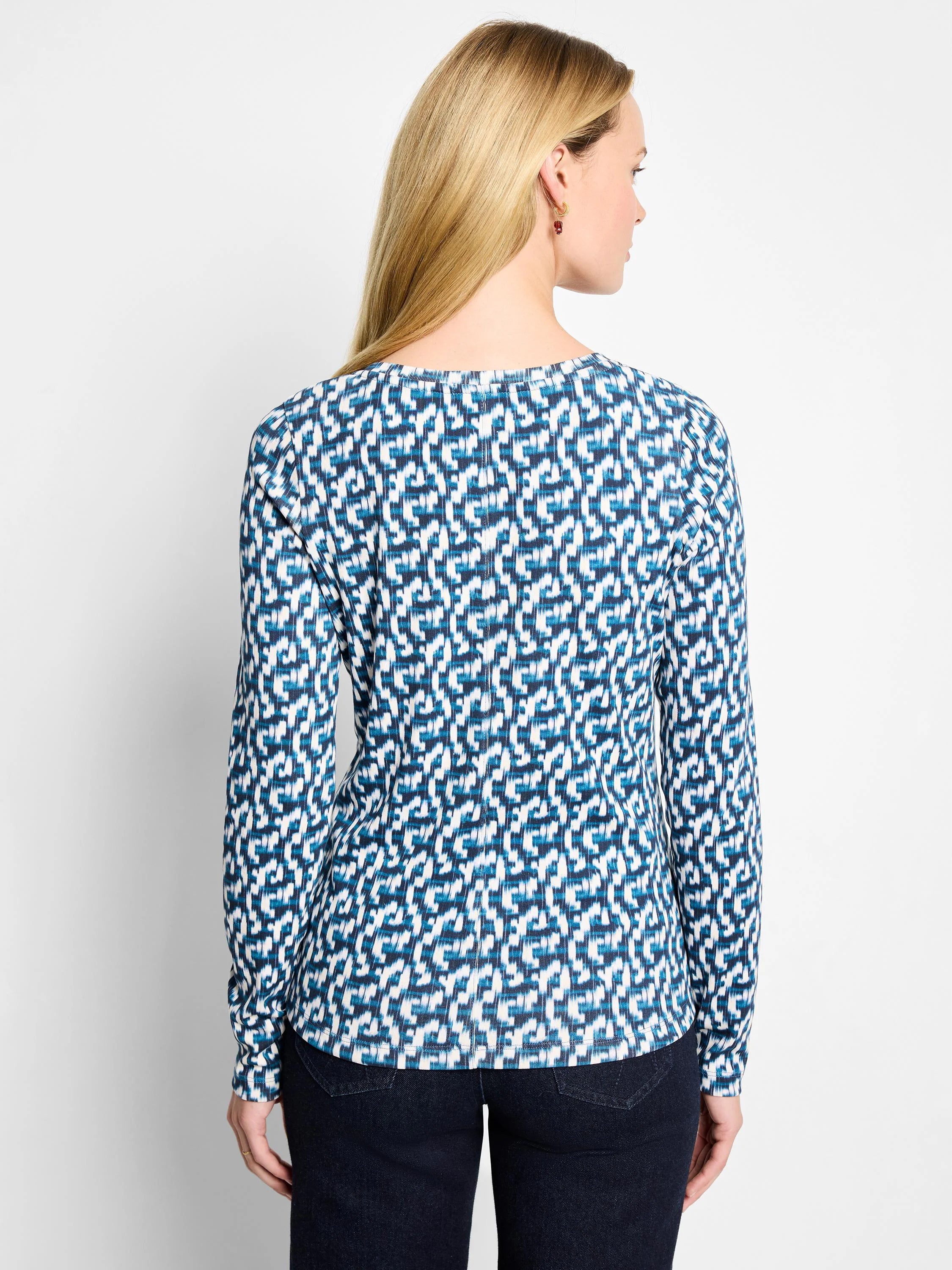 Back view of a white long sleeve boat neck tee with an abstract geometric print in shades of blue.