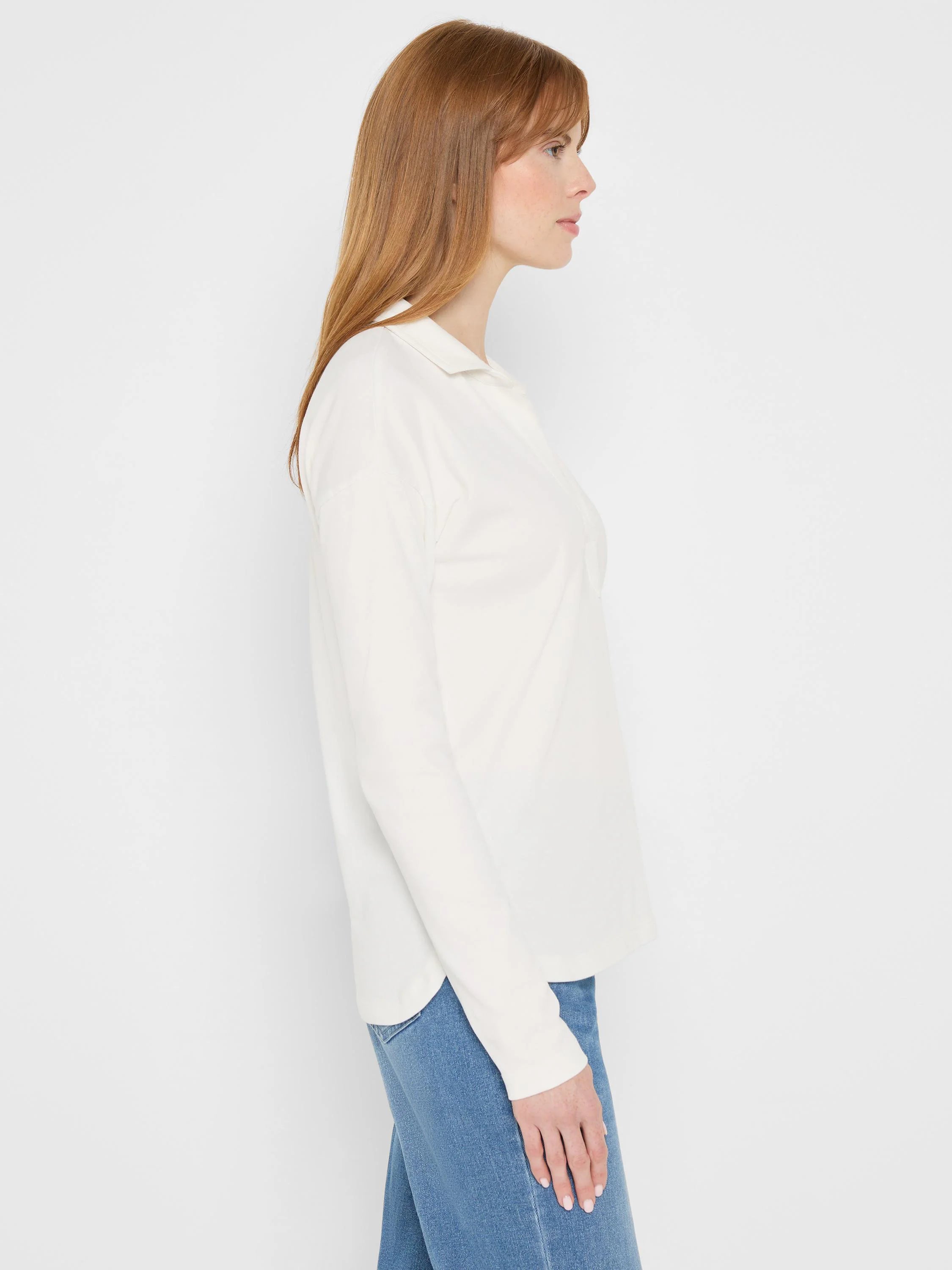 Off-white long-sleeve polo top with collar and open placket, shown on a model in profile.