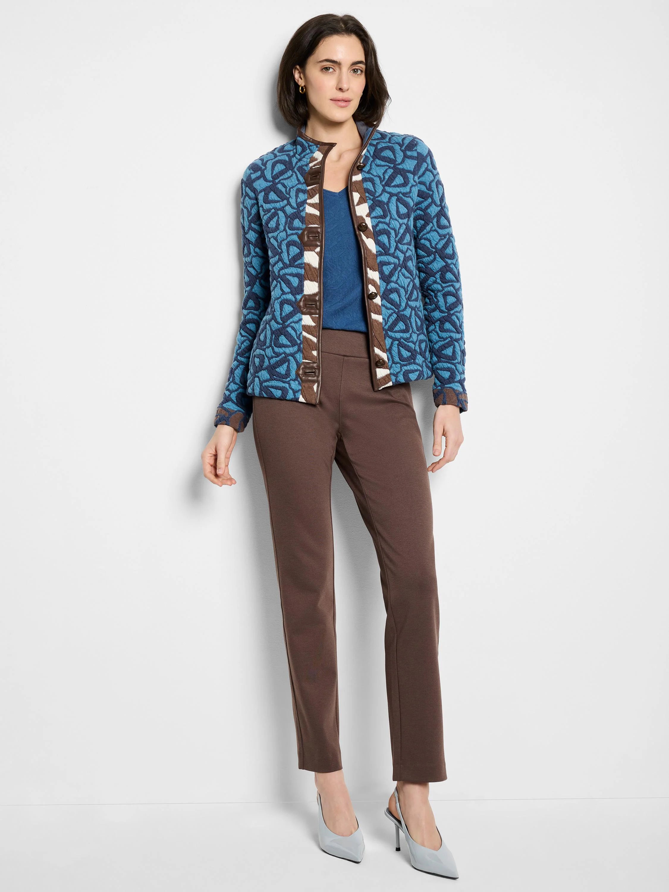 Blue V-neck knit top with darker blue and brown patterned detailing. Brown pants and light blue shoes are also shown.