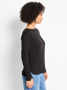 Black long-sleeve knit top with boat neck and rounded hem with small side slits.